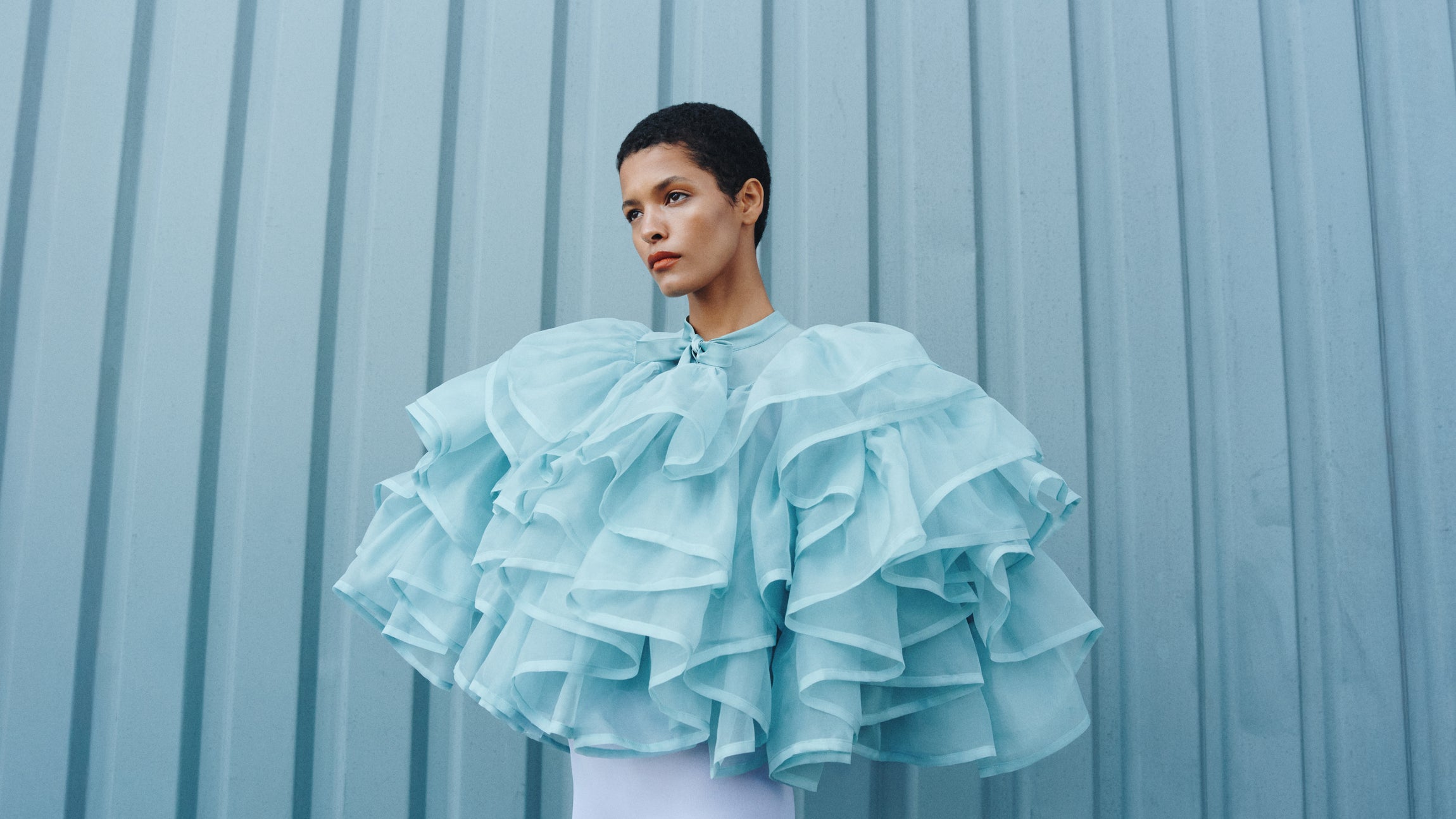 Woman wearing a light blue ruffled top against a light blue background