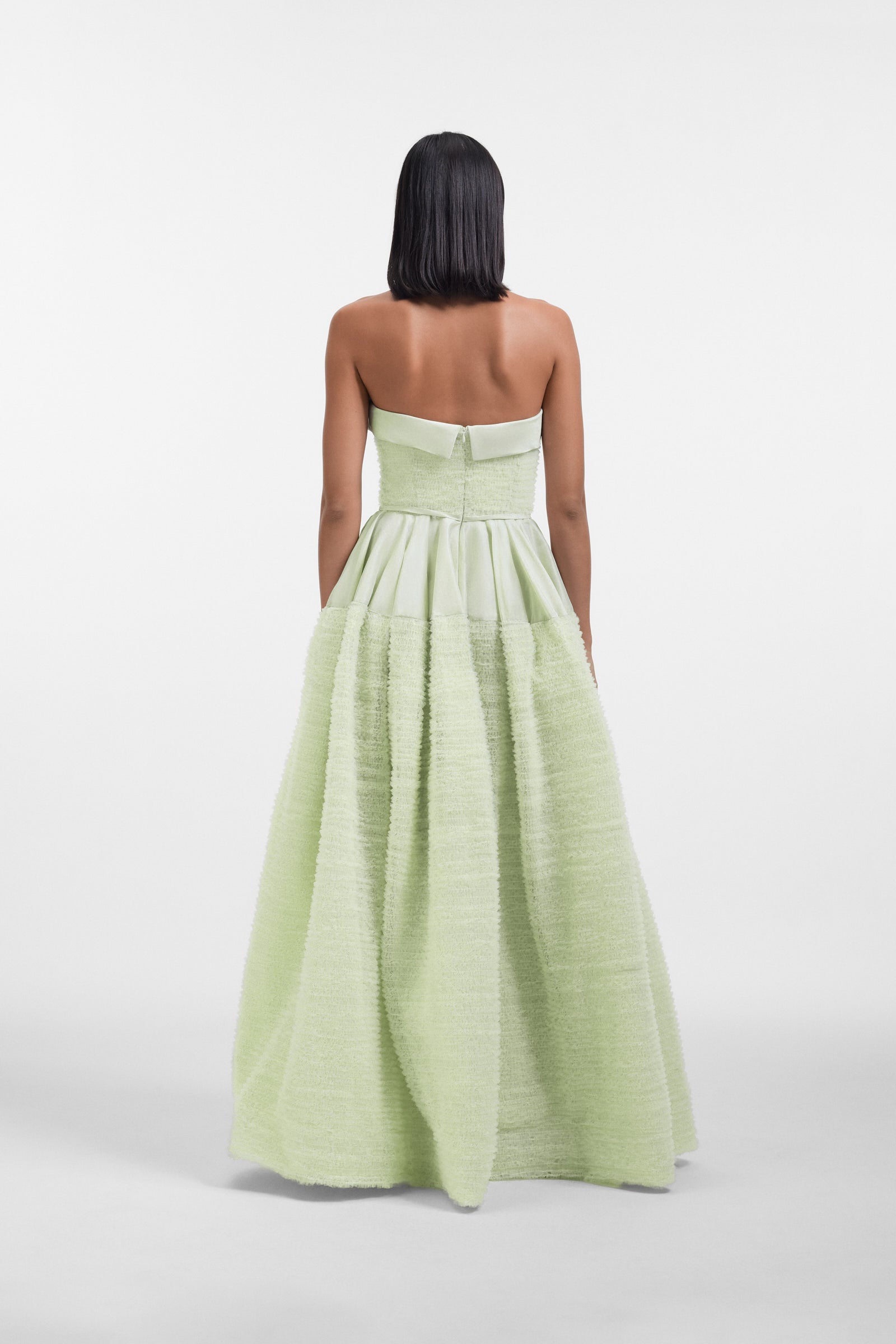 Model wearing a mint green strapless tulle gown on a white background.
