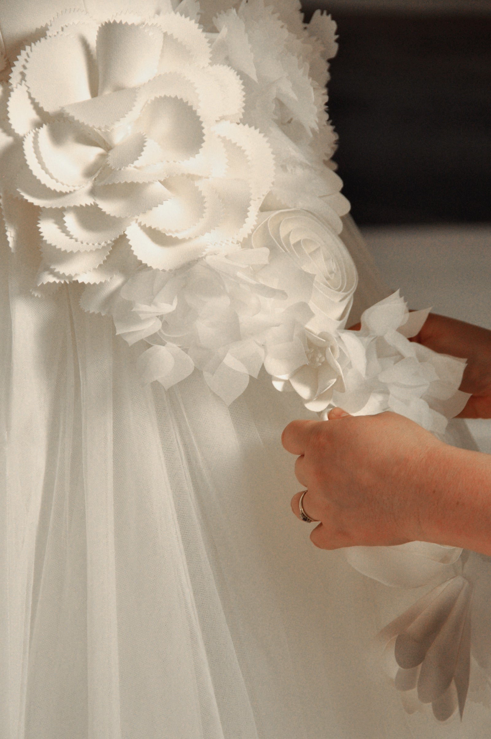Close-up on a floral detail of a white wedding gown.