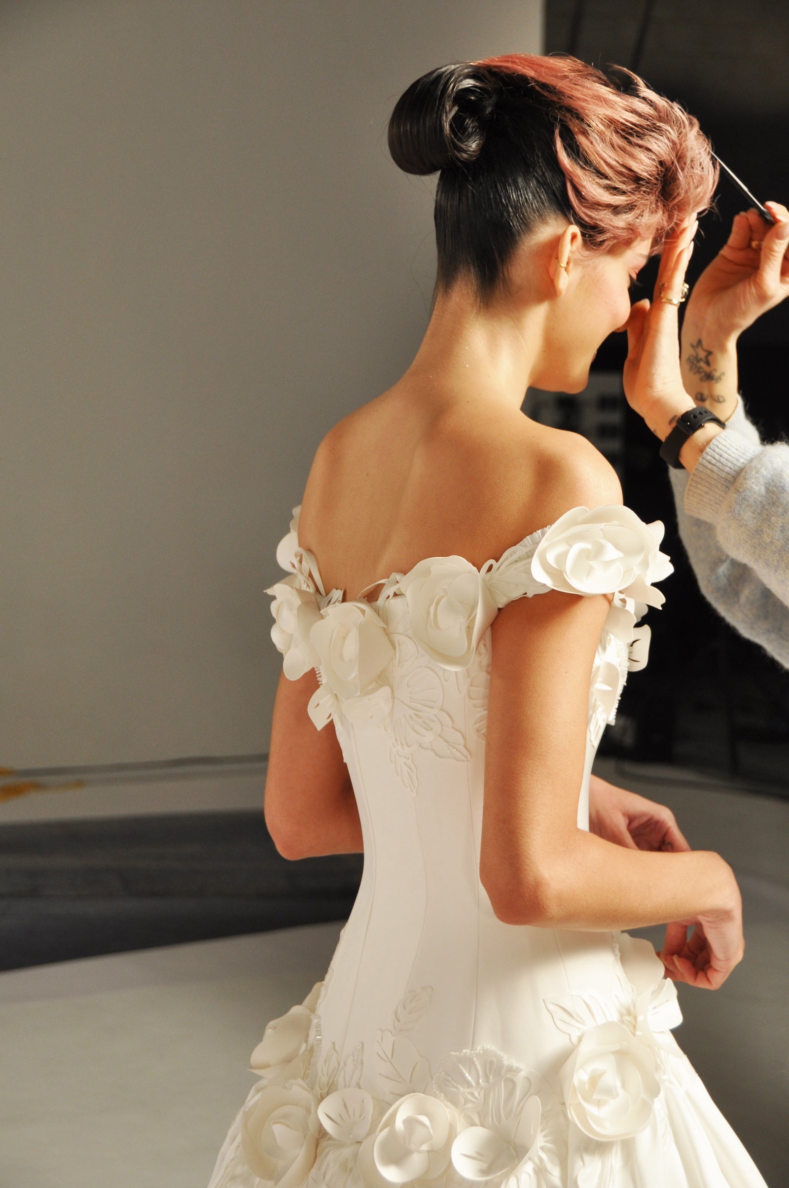 Model wearing a white strapless wedding gown with floral elements.