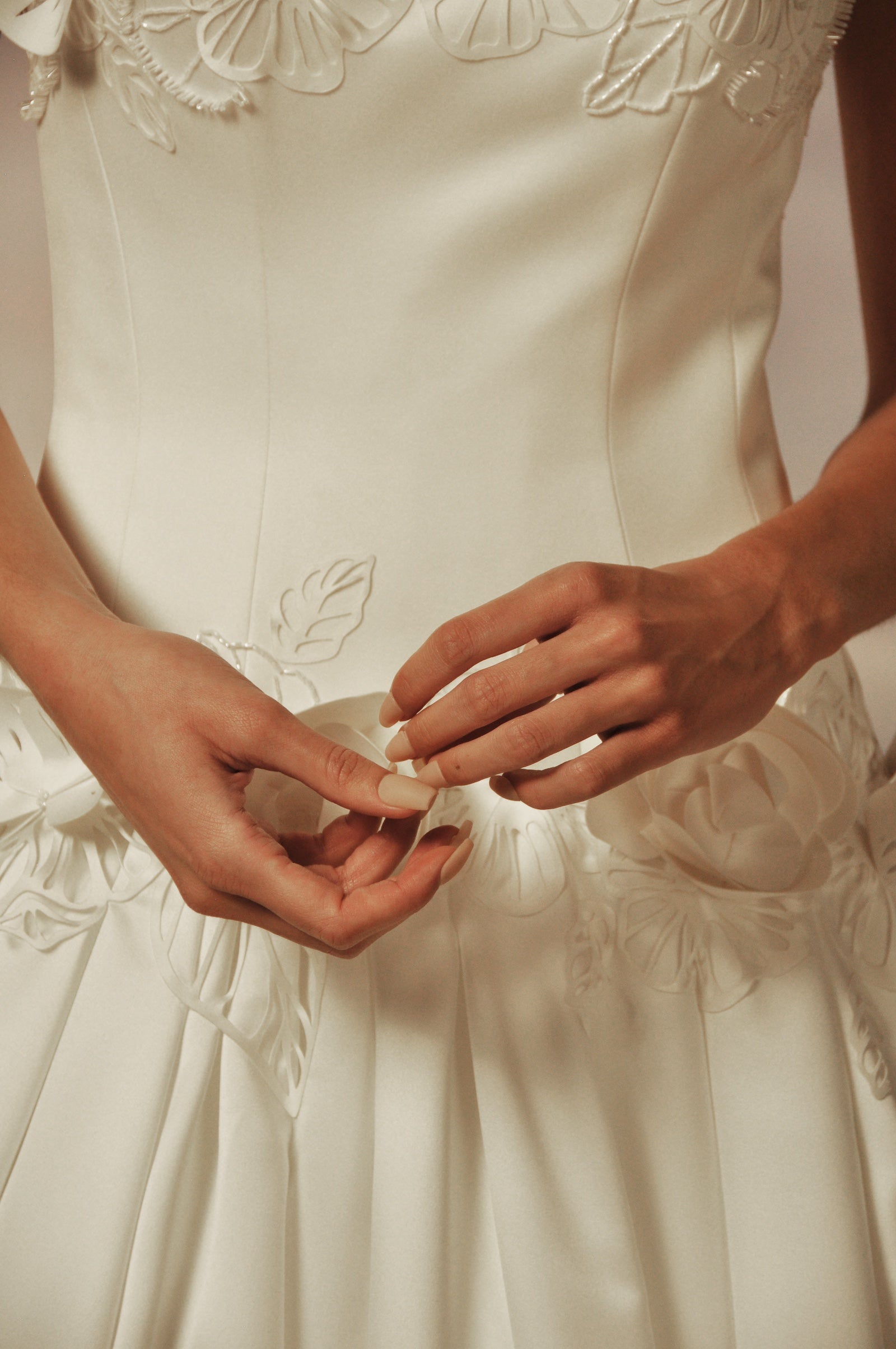 Close-up on a model wearing a white floral wedding gown.