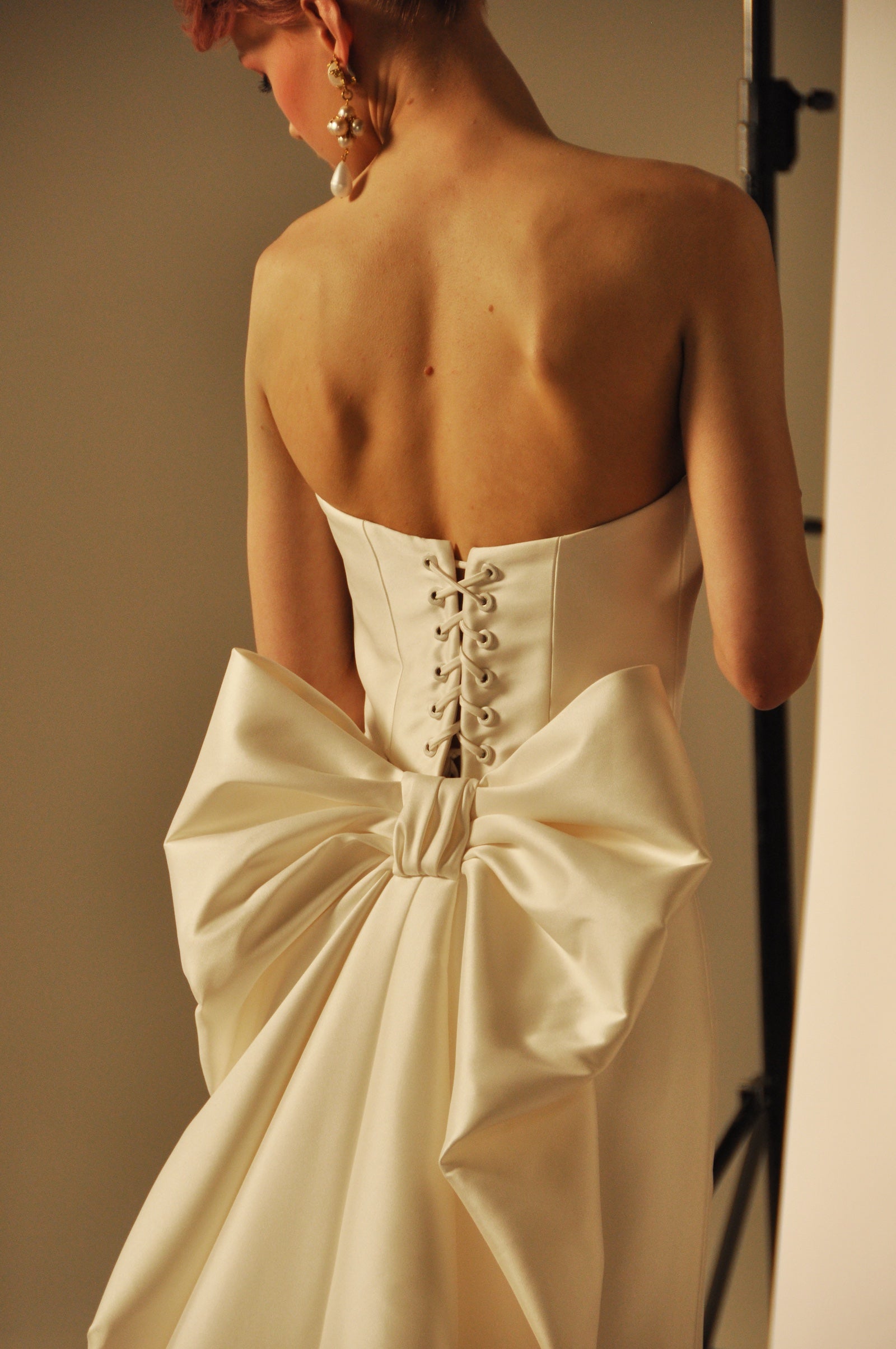 Close-up shot on a model wearing a bridal gown with a bow on the back.