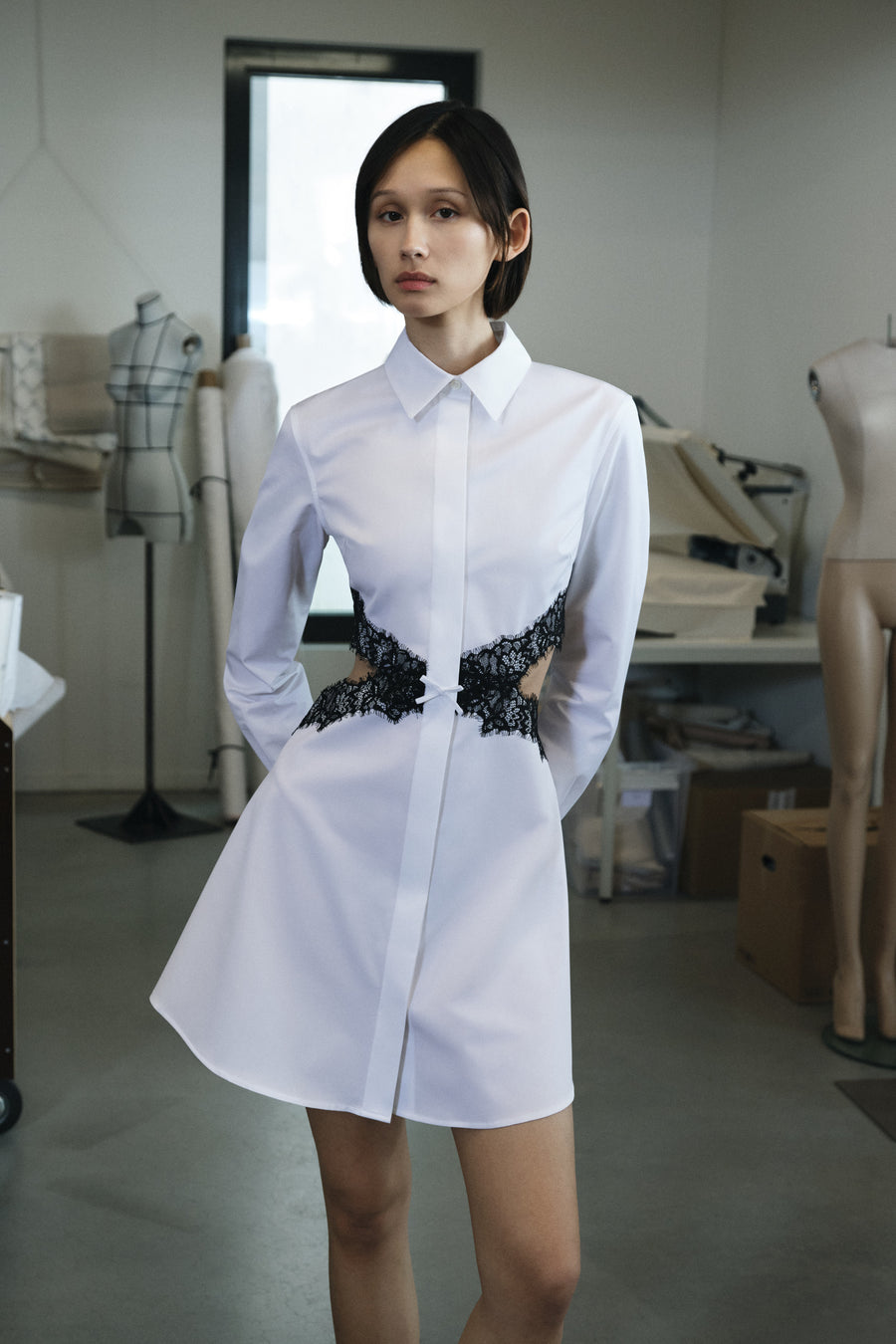 Woman wearing a white dress with black embellishments in a studio setting