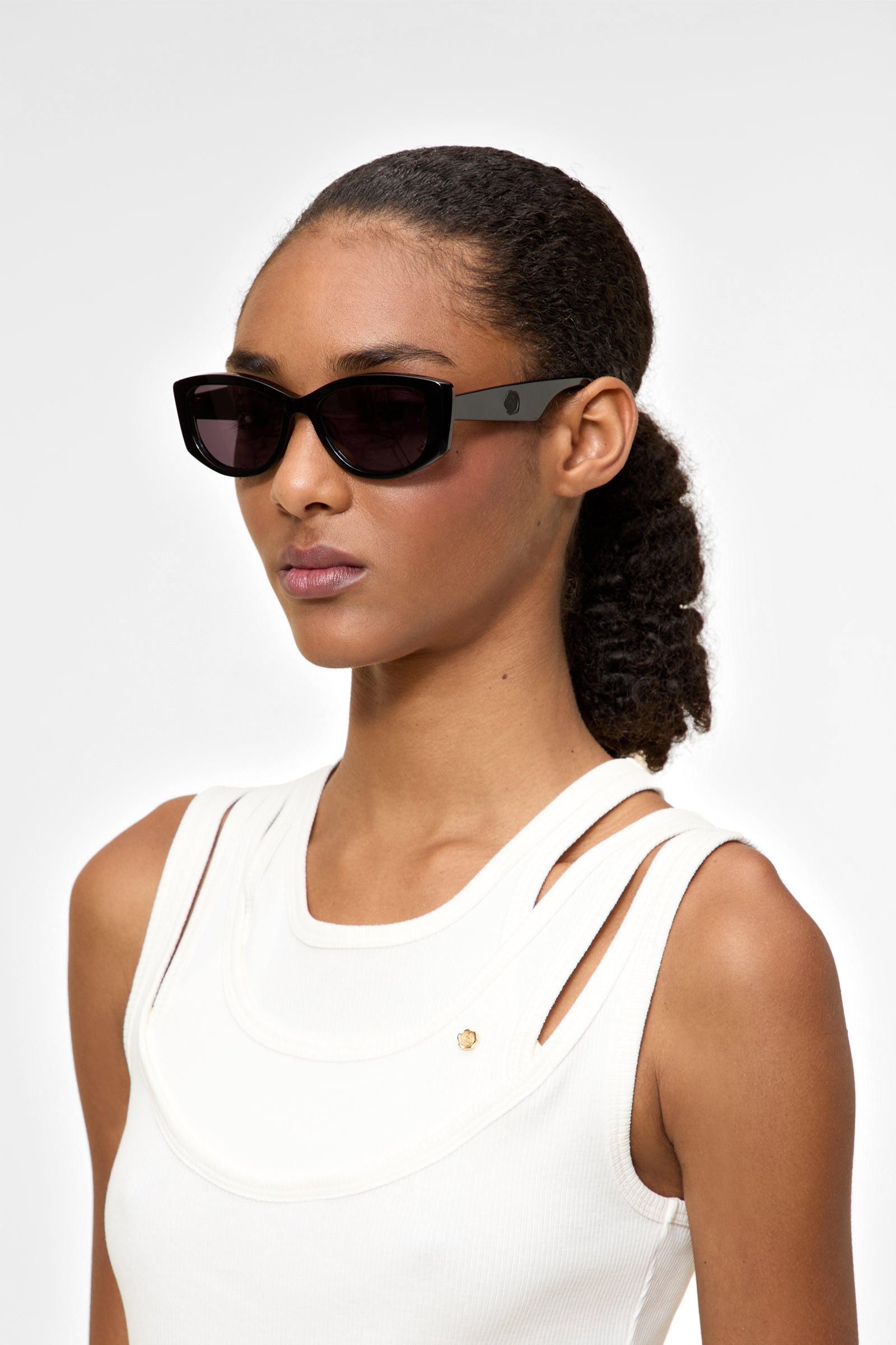 Model wearing semi-oval black sunglasses on a white background.