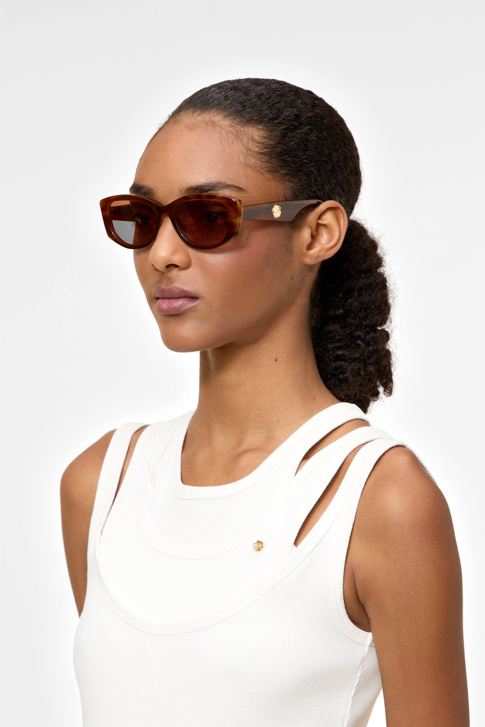 Model wearing light tortoise sunglasses on a white background.