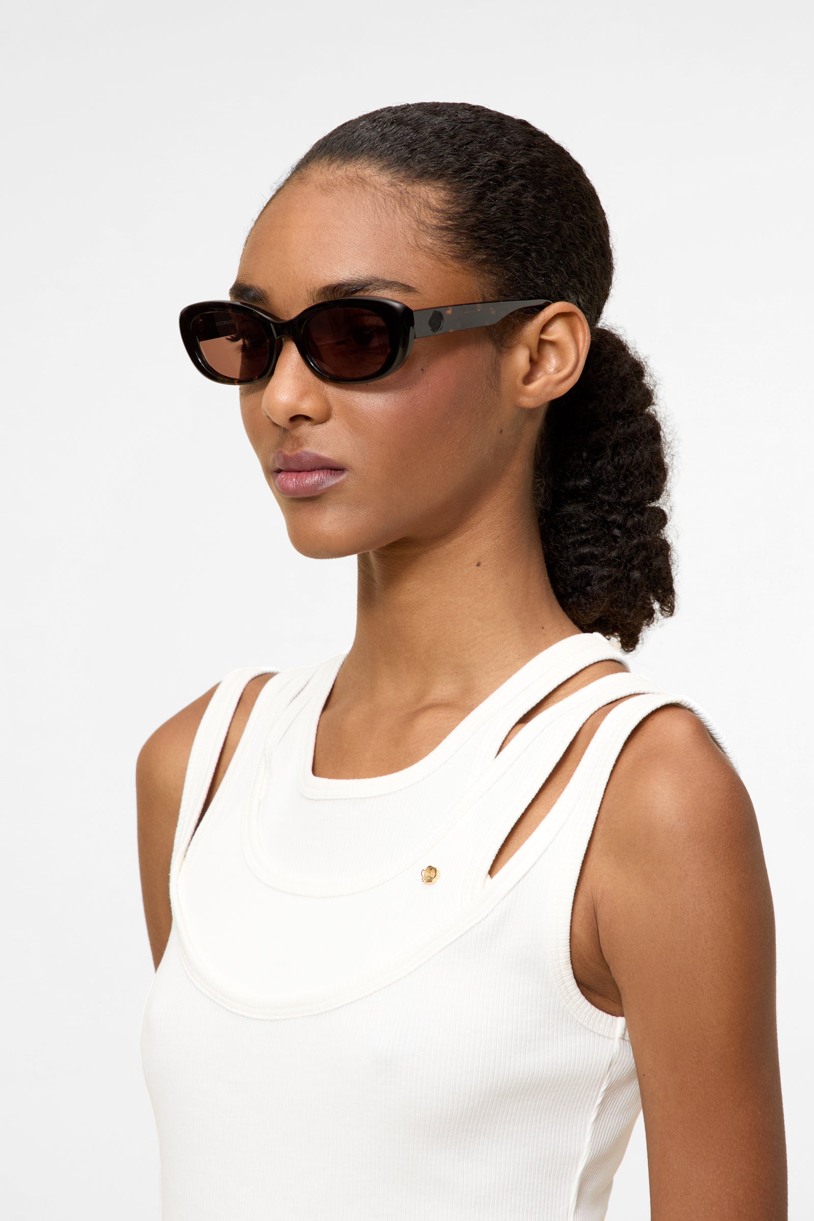 Model wearing tortoise oval sunglasses.