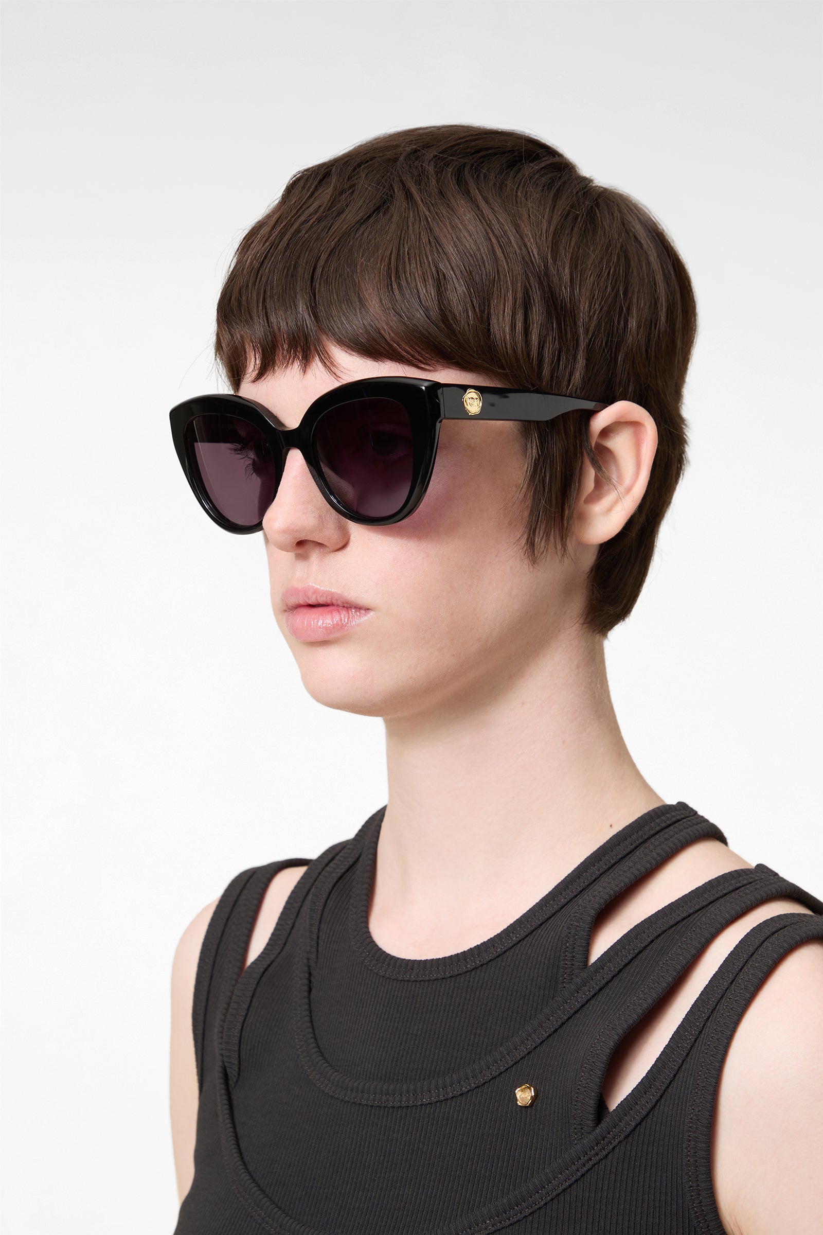 Model wearing black cat-eye sunglasses on a white background.
