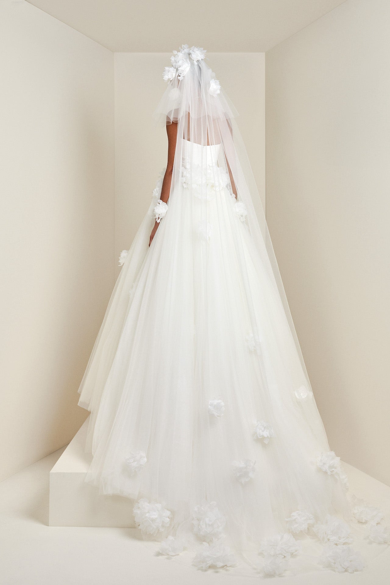 Featuring a voluminous tiered design, this tulle veil is adorned with feathered organza hortensia flowers cascading down the veil