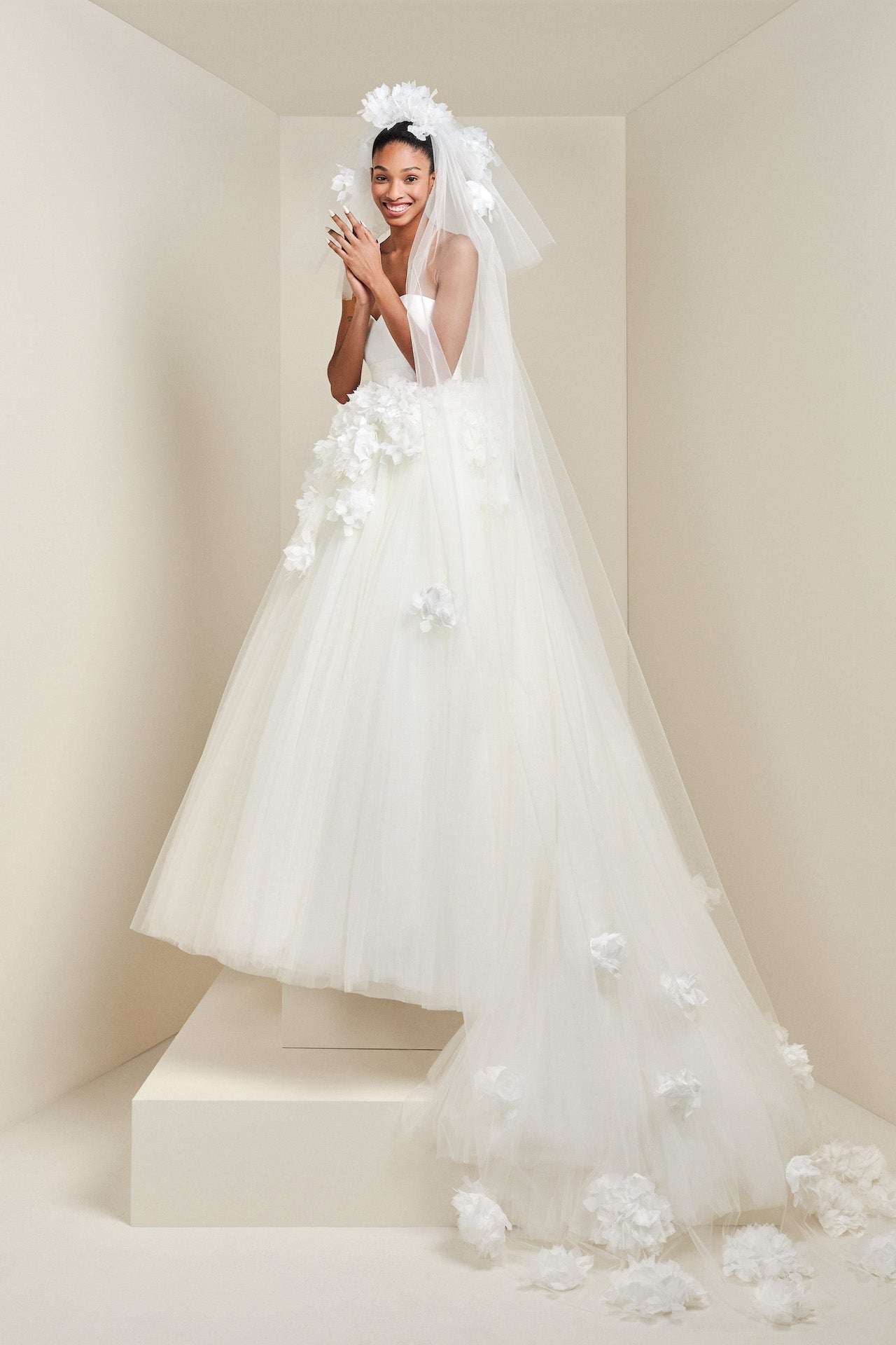 Featuring a voluminous tiered design, this tulle veil is adorned with feathered organza hortensia flowers cascading down the veil