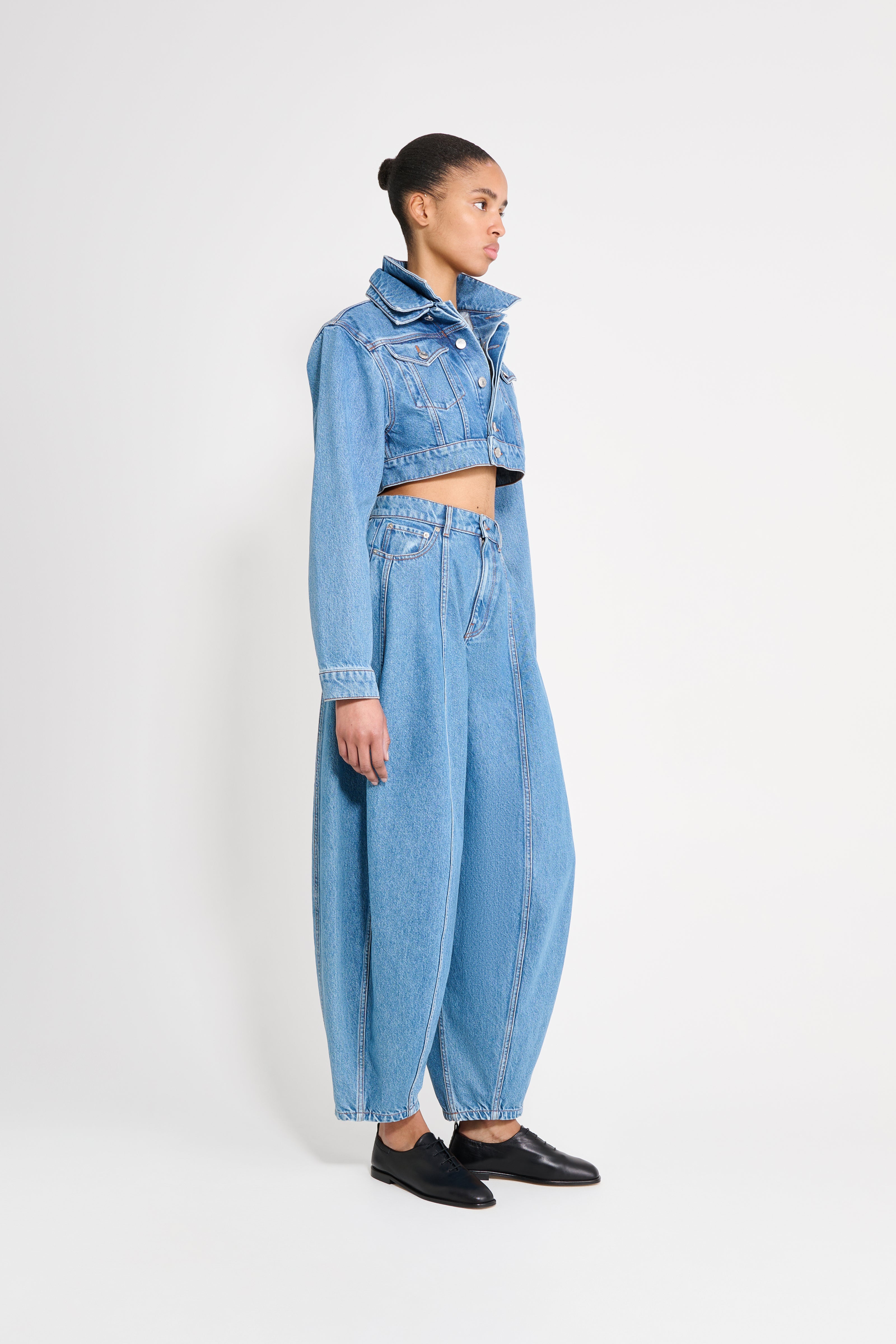 Person wearing a light blue denim outfit on a white background