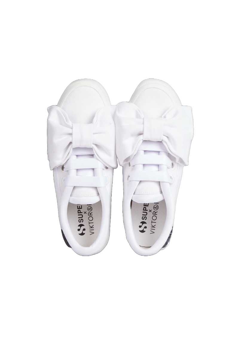 White canvas sneakers adorned with oversized fabric bows, featuring a branded insole from a designer collaboration.