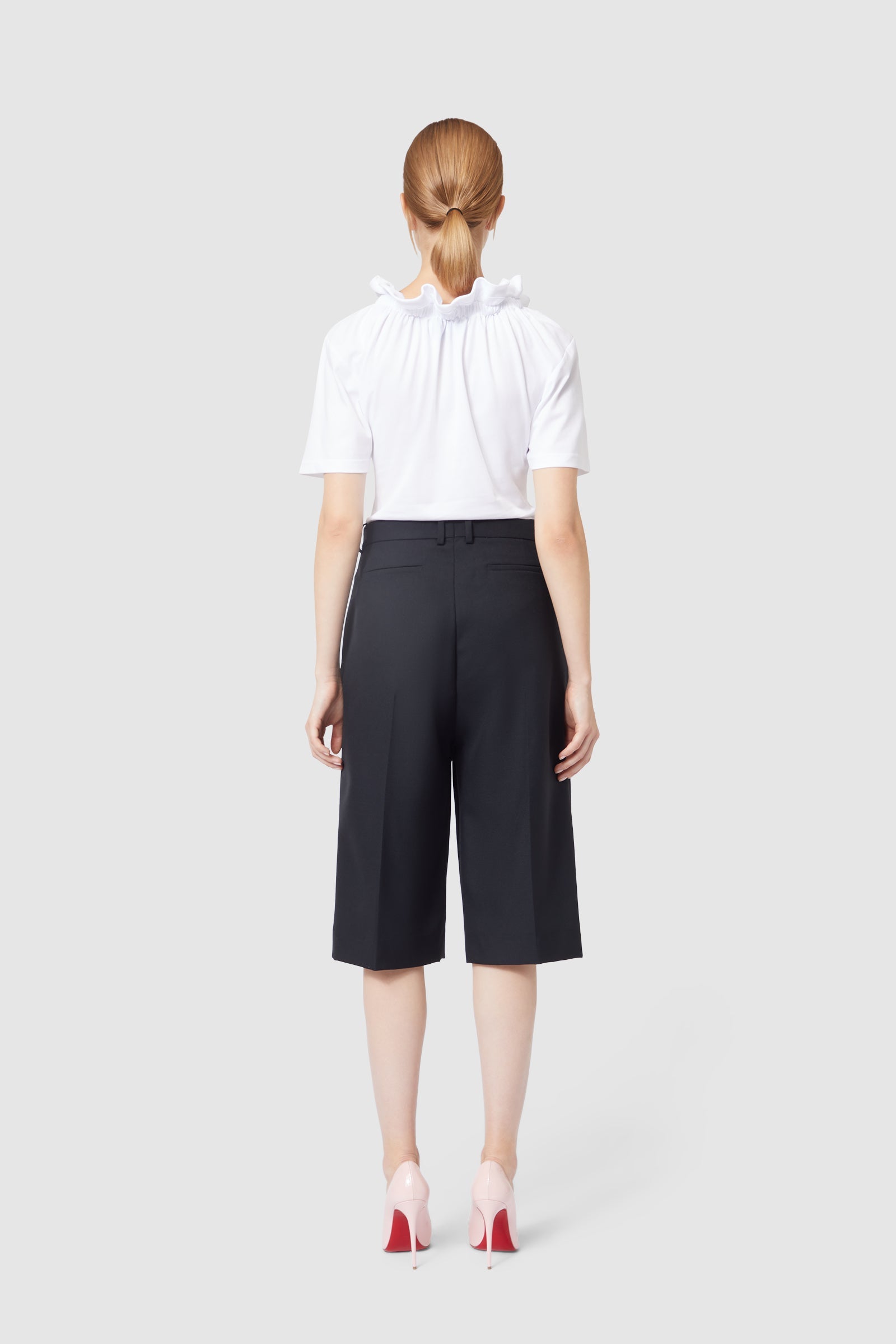 Elegant white ruffled blouse paired with high-waisted black culottes, showcasing a minimalist, sophisticated style.