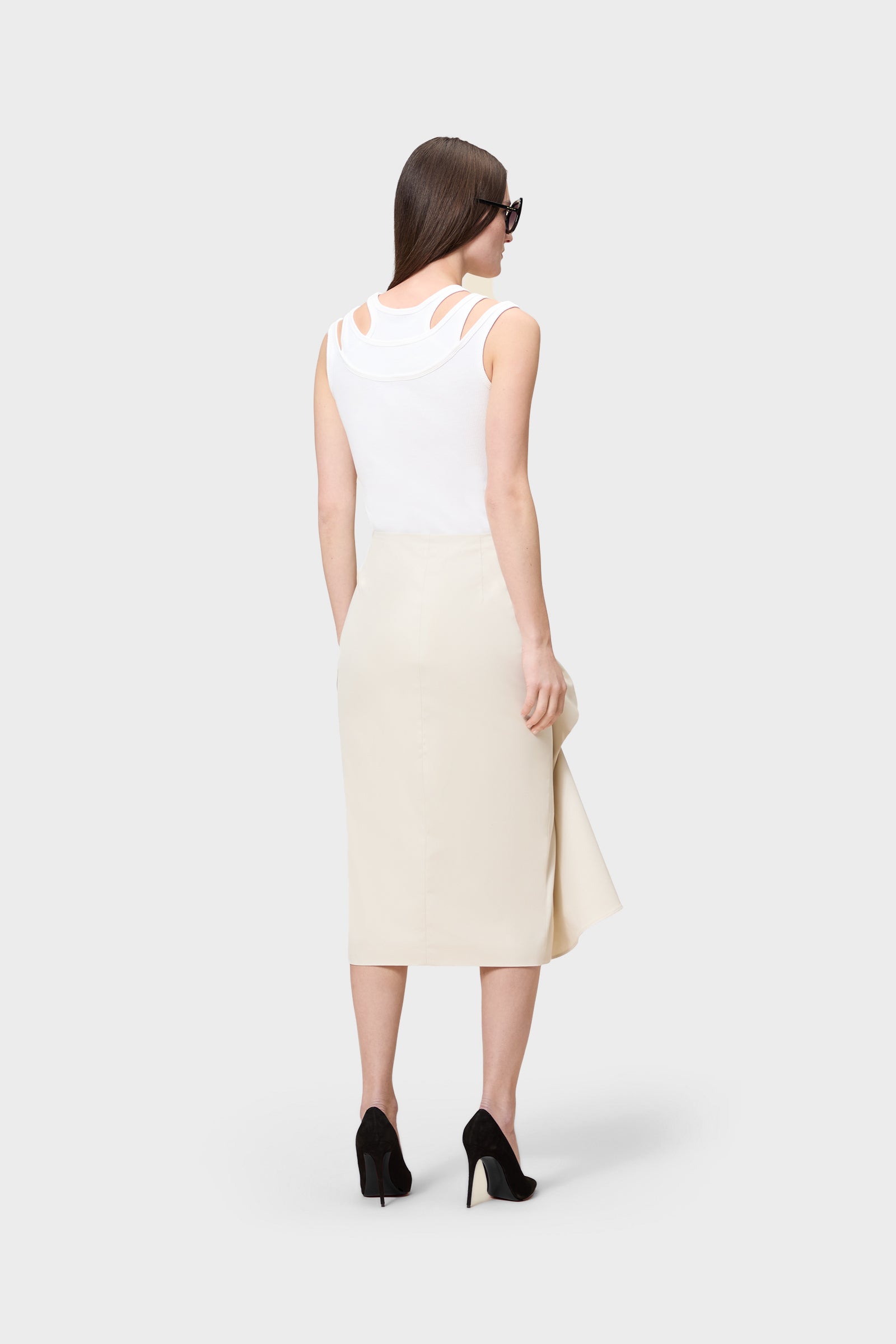 Model wearing a white top with a beige skirt on a white background.