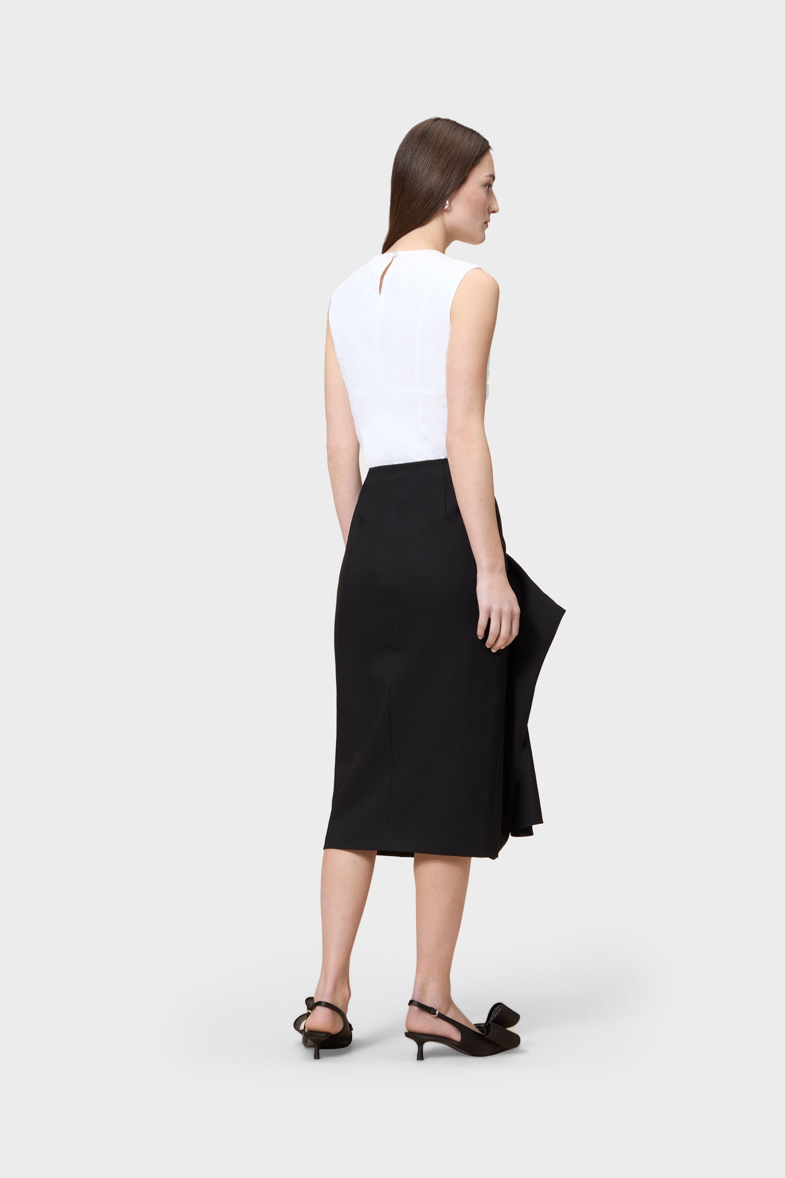Model wearing a white shirt with black skirt on a white background.