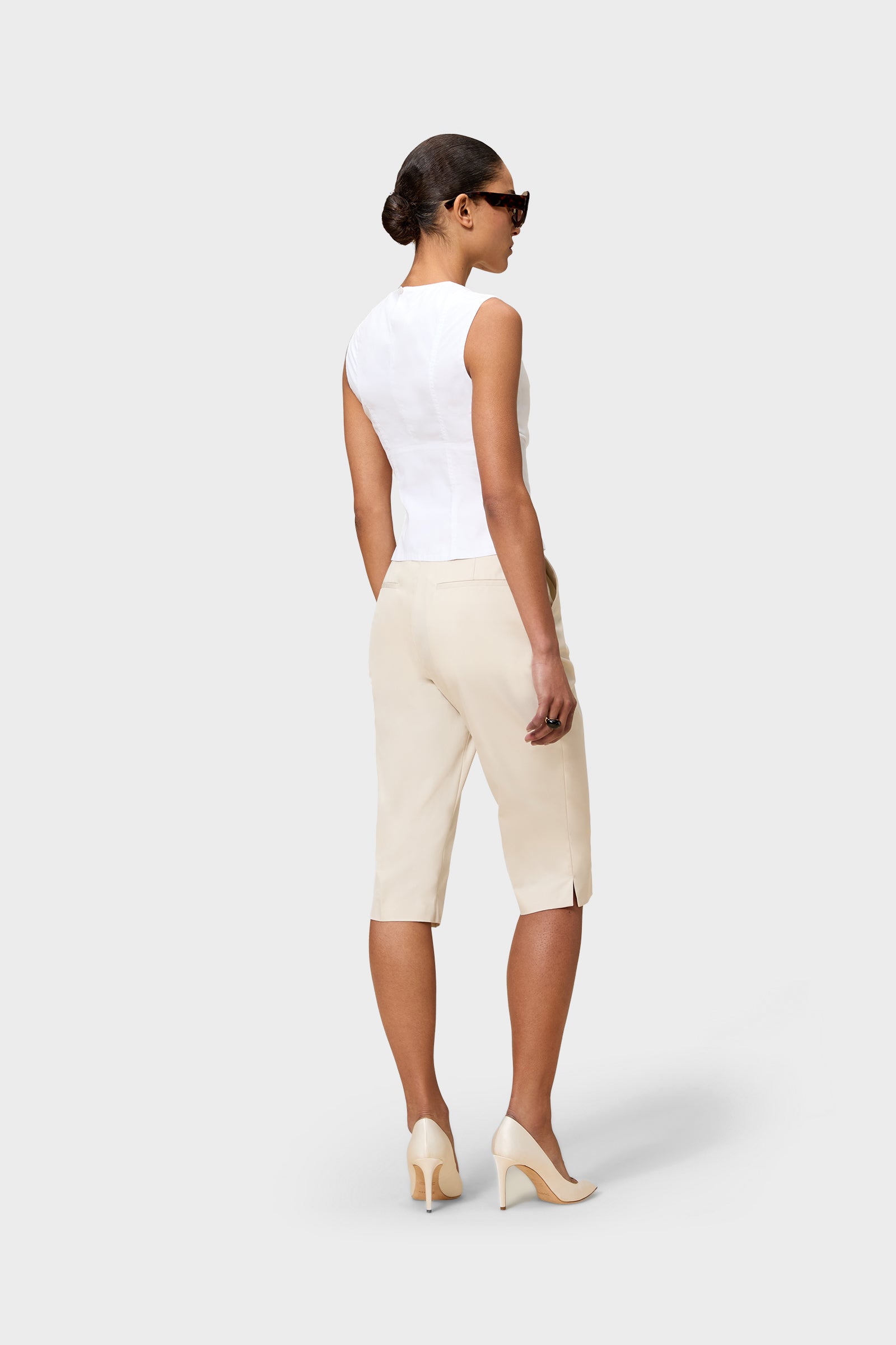 Model wearing a white top and beige capri pants on a white background.