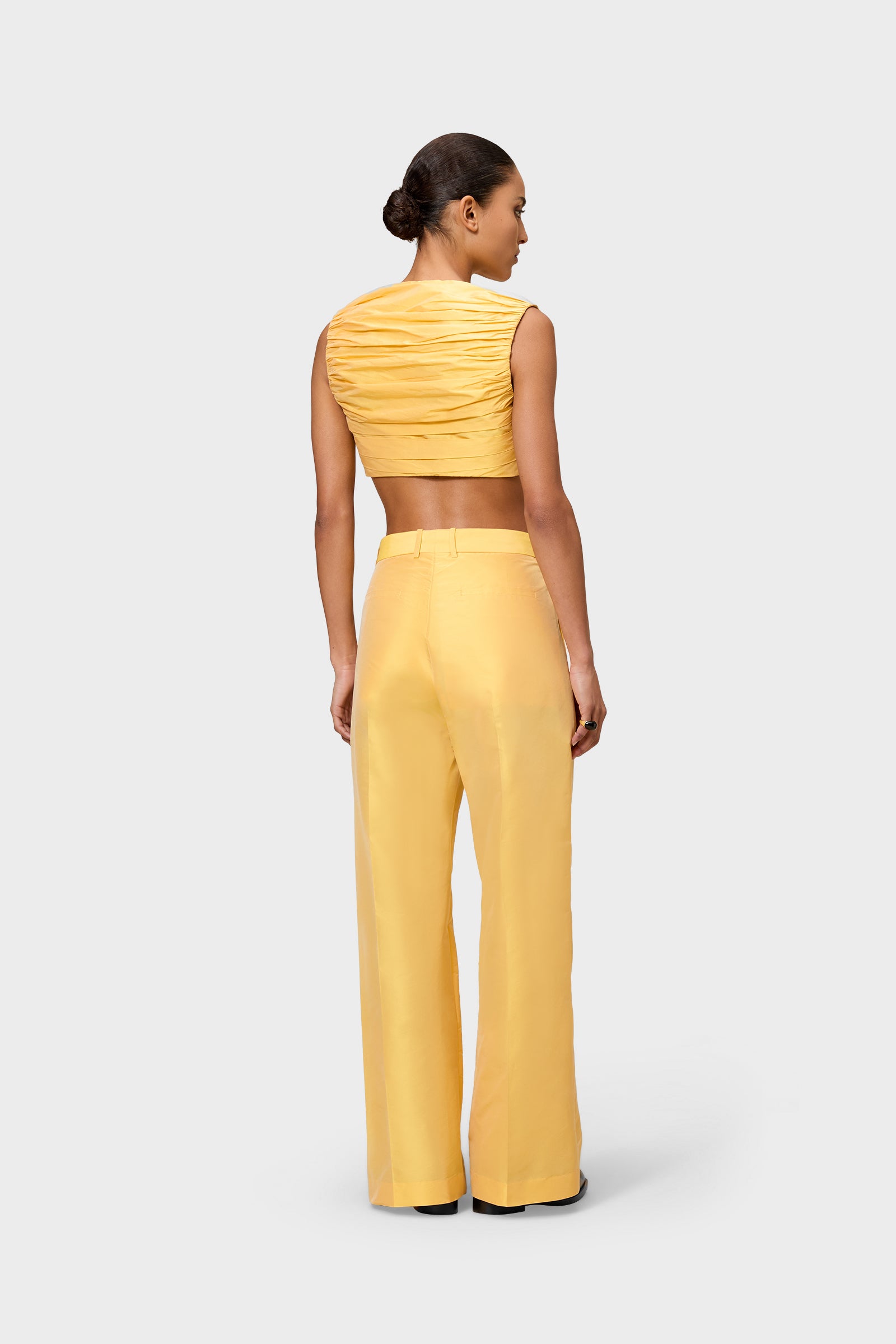 Model wearing a yellow satin set on a white background.