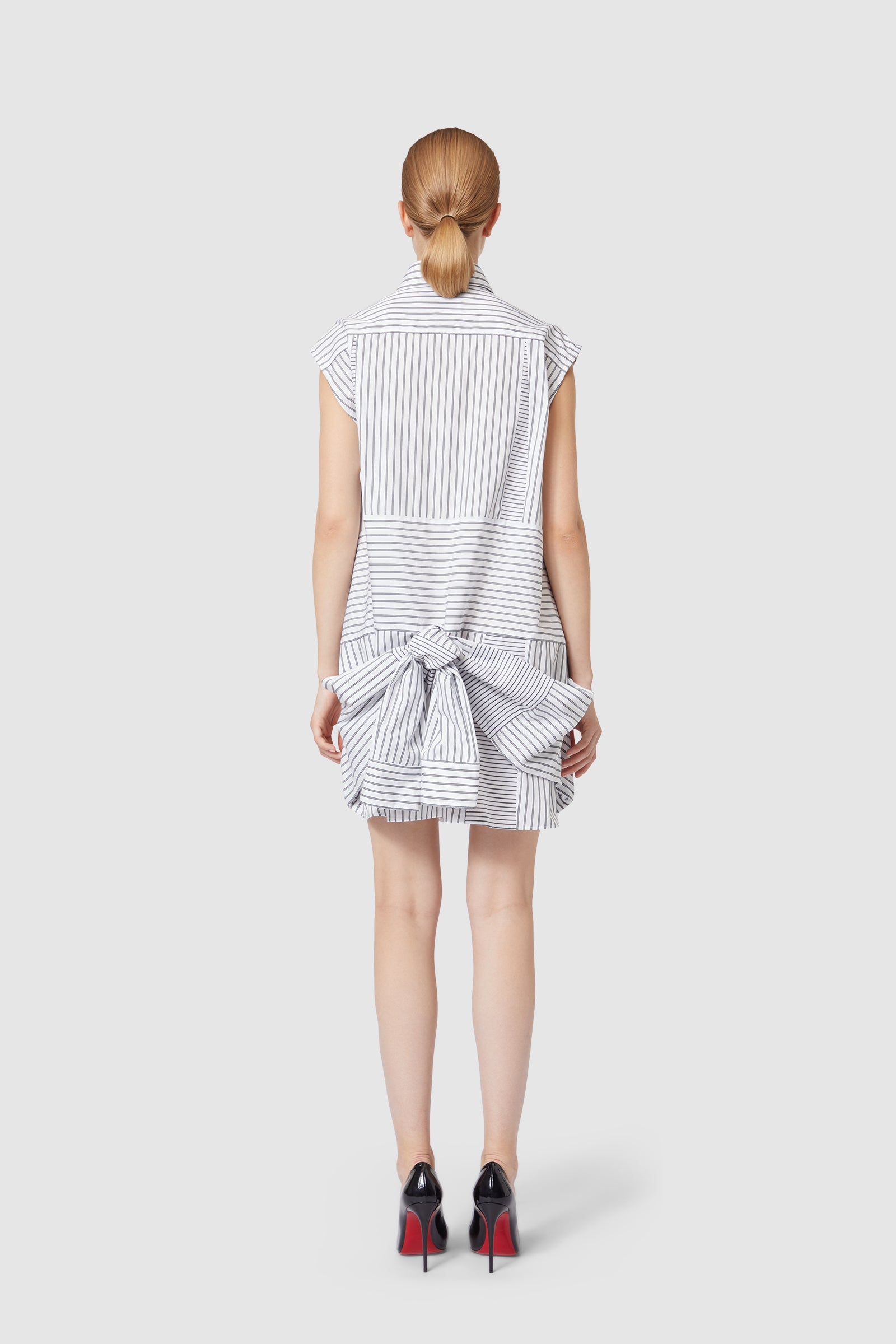 Striped sleeveless shirtdress with bow accent at back, showcasing a mix of vertical and horizontal lines on cotton fabric.