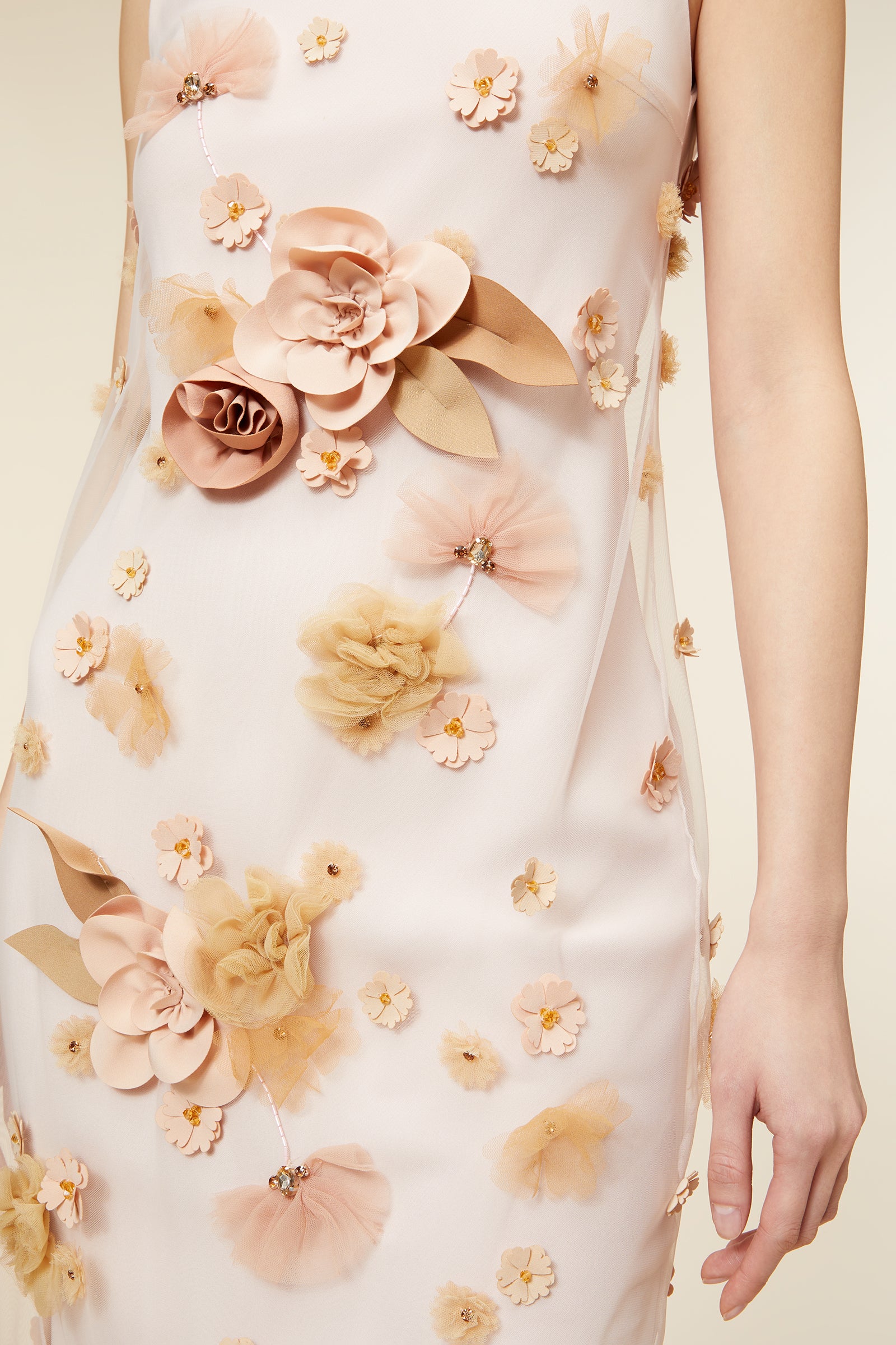 Elegant sleeveless dress with floral appliqué detailing in soft pastel tones, featuring a sheer overlay and classic silhouette.
