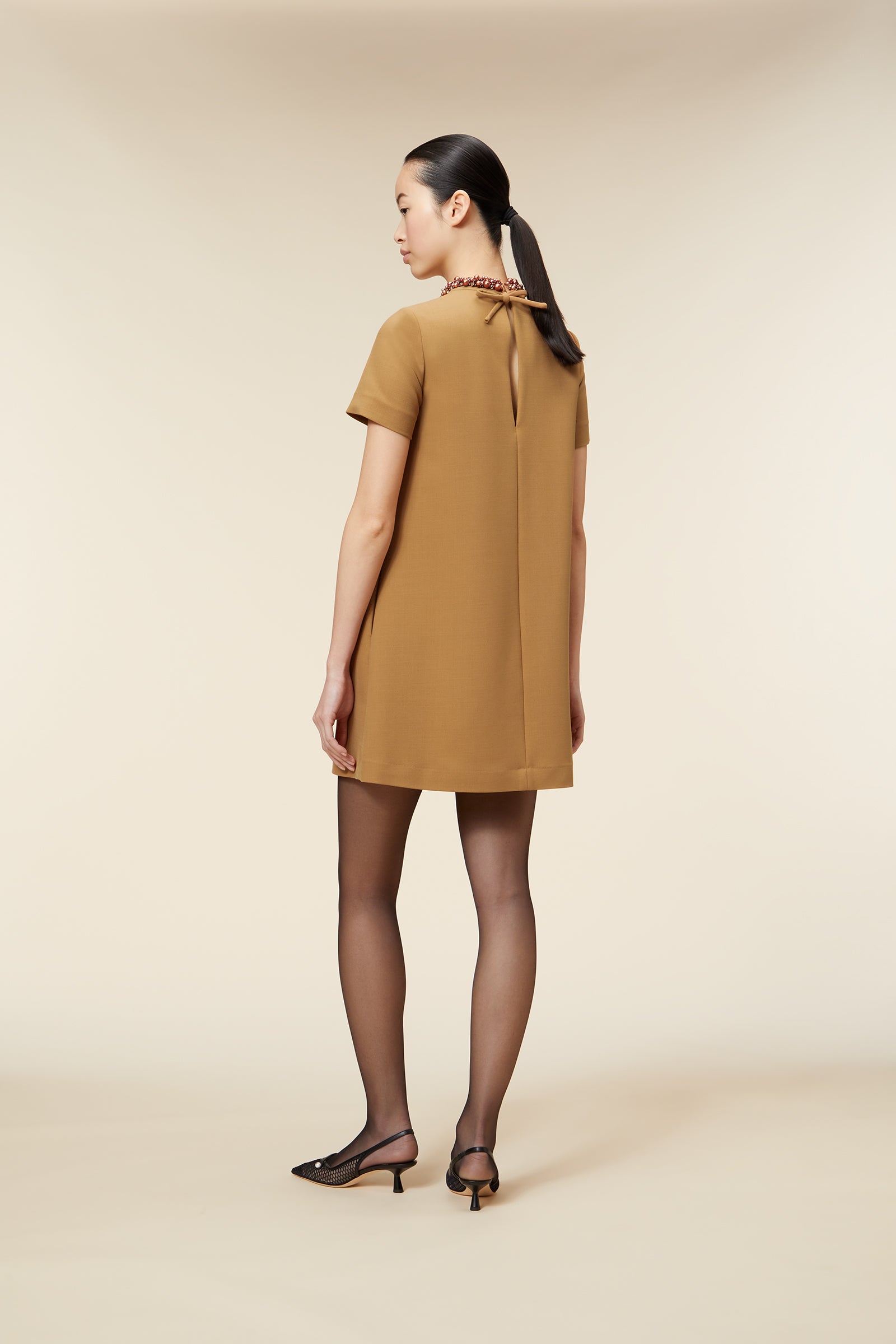 Elegant mustard-colored dress with beaded trim on pockets and collar, featuring short sleeves and a straight silhouette.