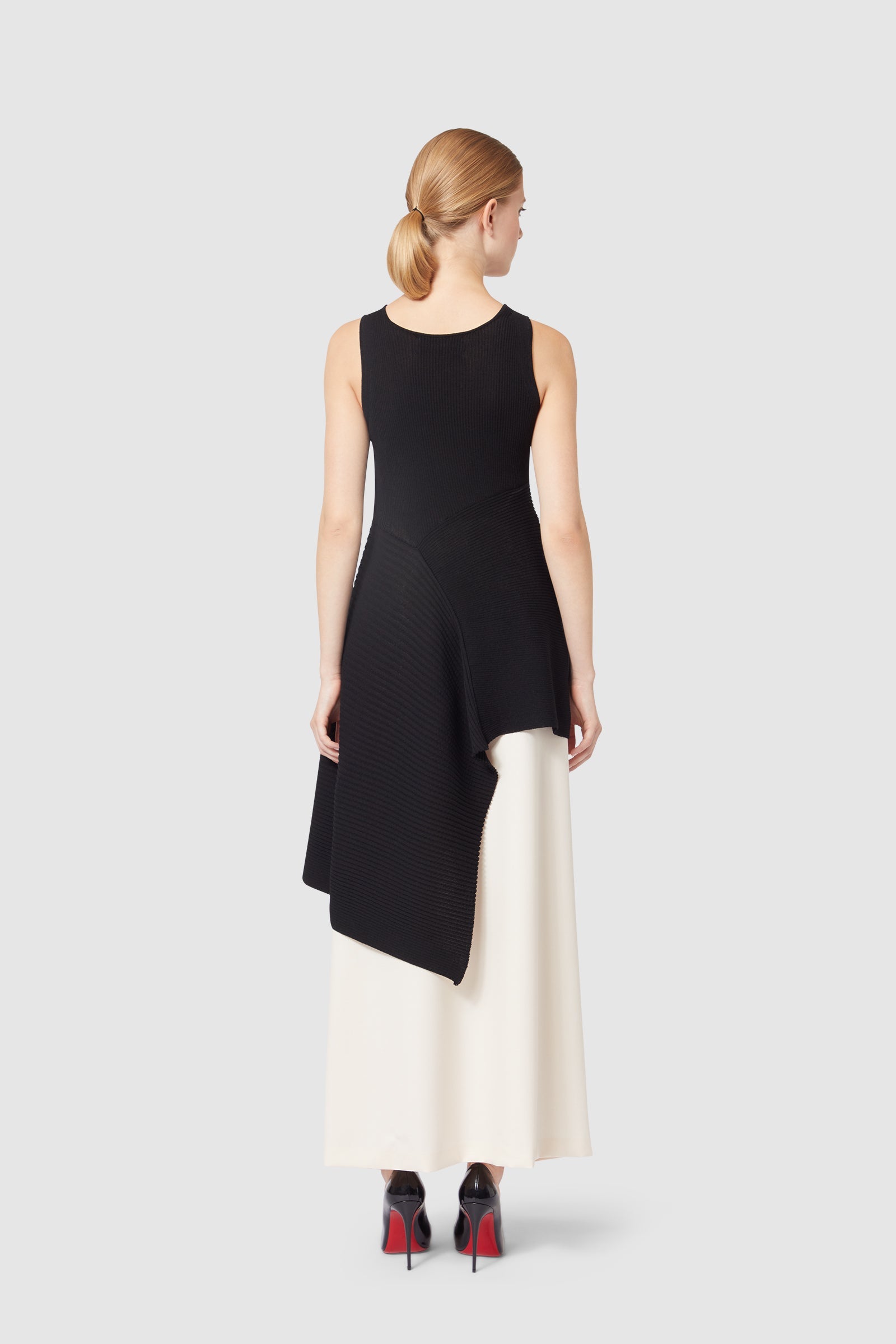 Asymmetrical black knit top paired with elegant white skirt, showcasing fluid lines and contrasting textures.