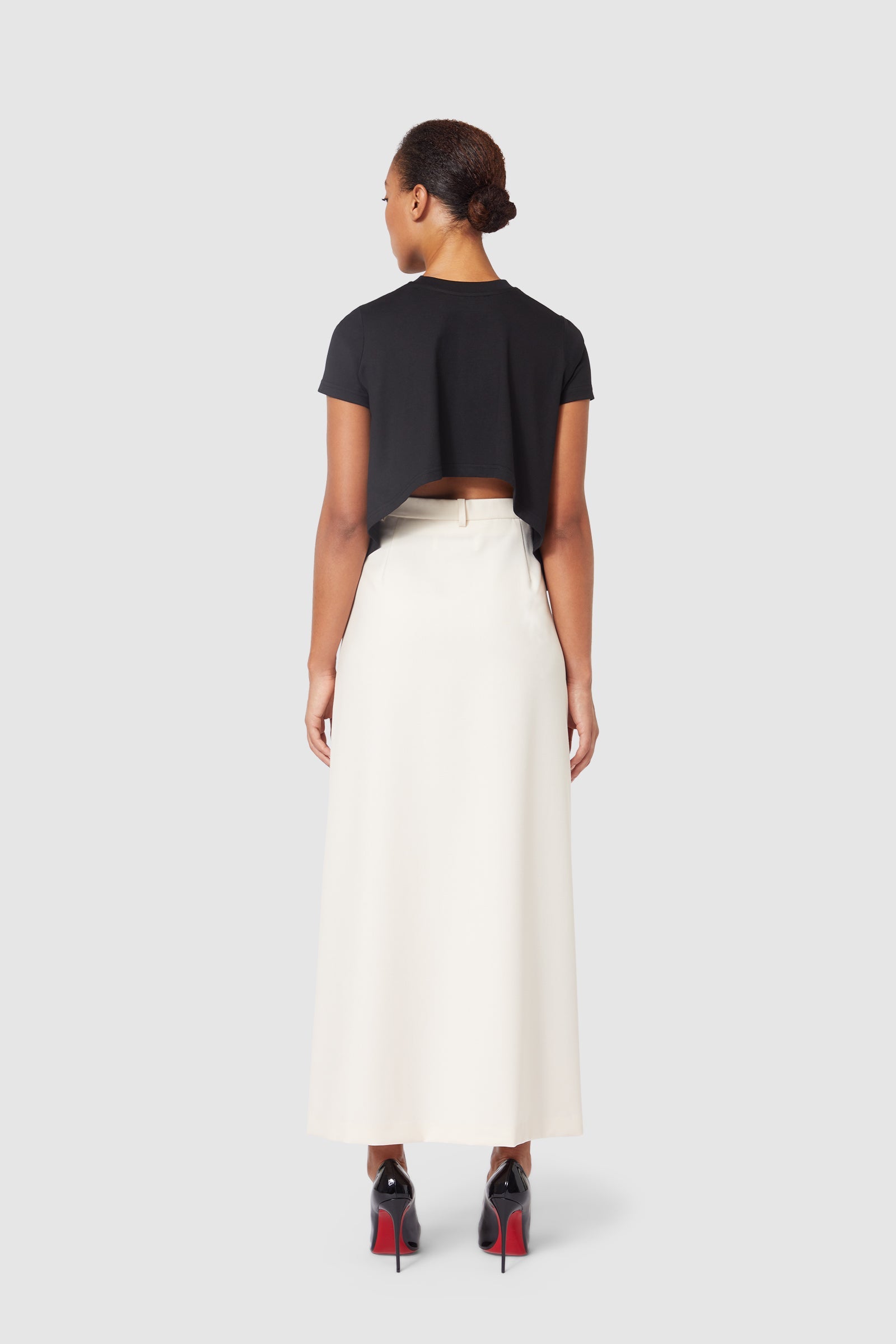 The ensemble features a sleek black cropped top paired with an elegant white high-waisted maxi skirt.