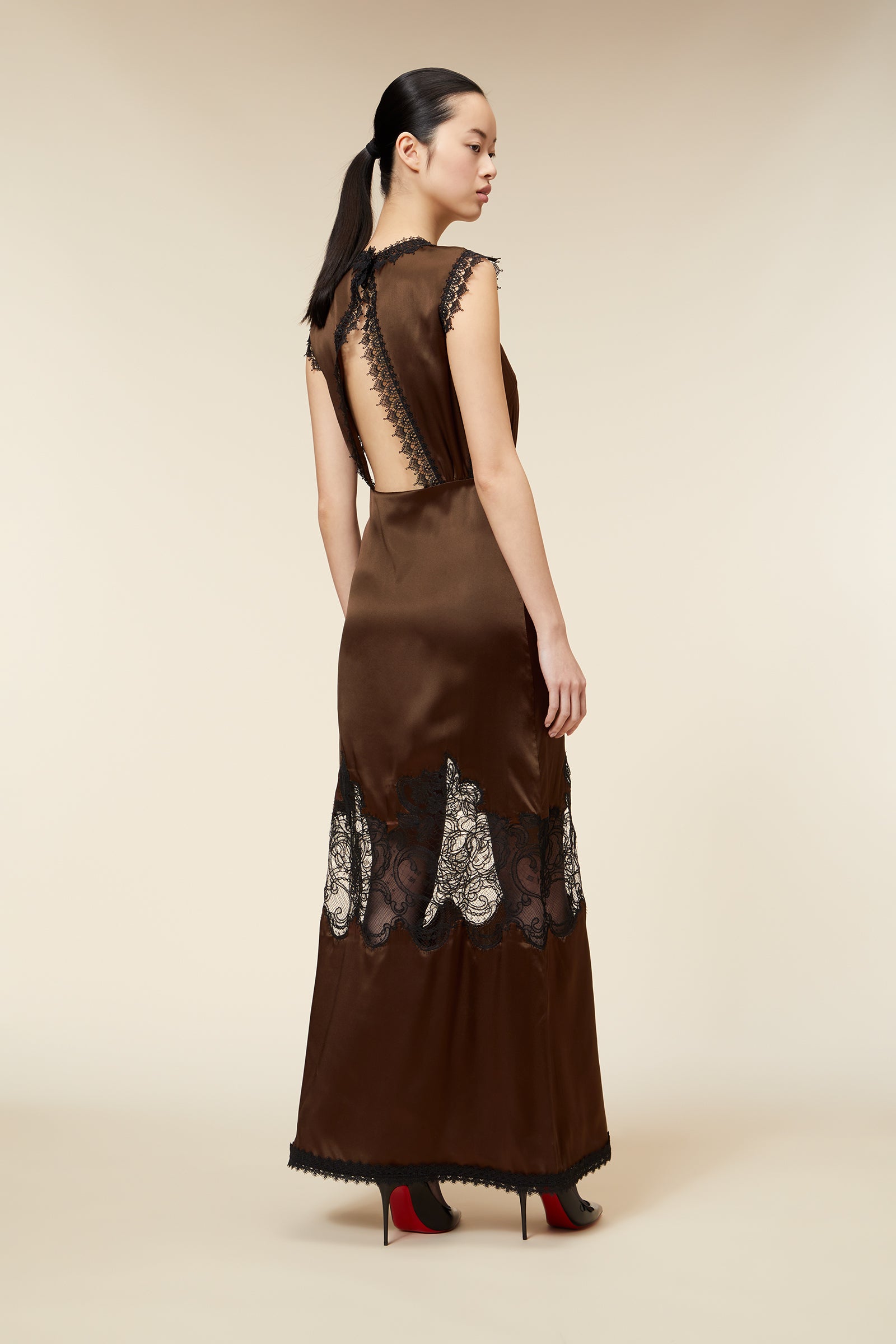 Luxurious brown satin gown featuring intricate black lace detailing and a dramatic back cutout accentuating elegance.