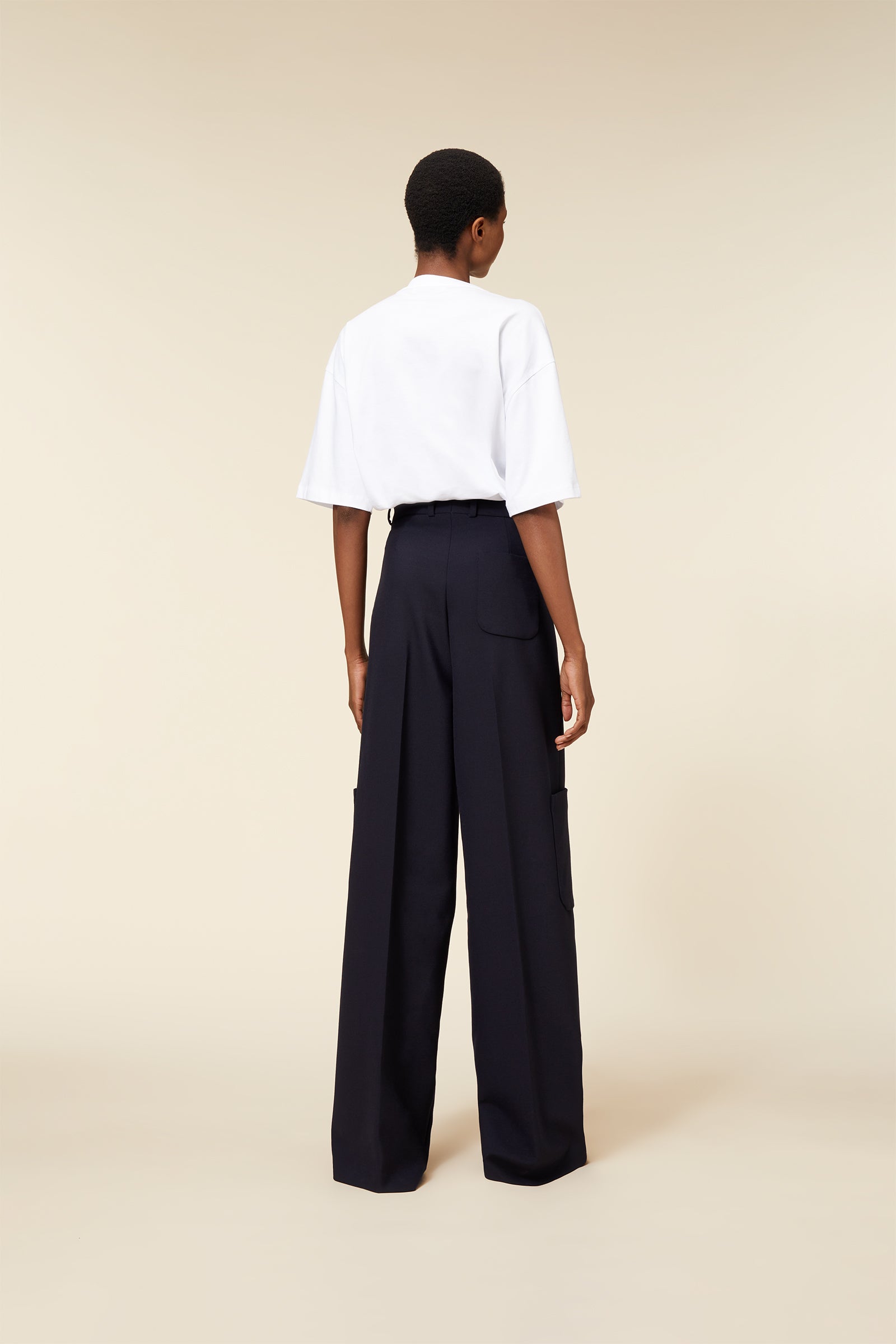 Wide-leg black tailored trousers with oversized pockets, paired with a relaxed-fit white T-shirt in a minimalist design.