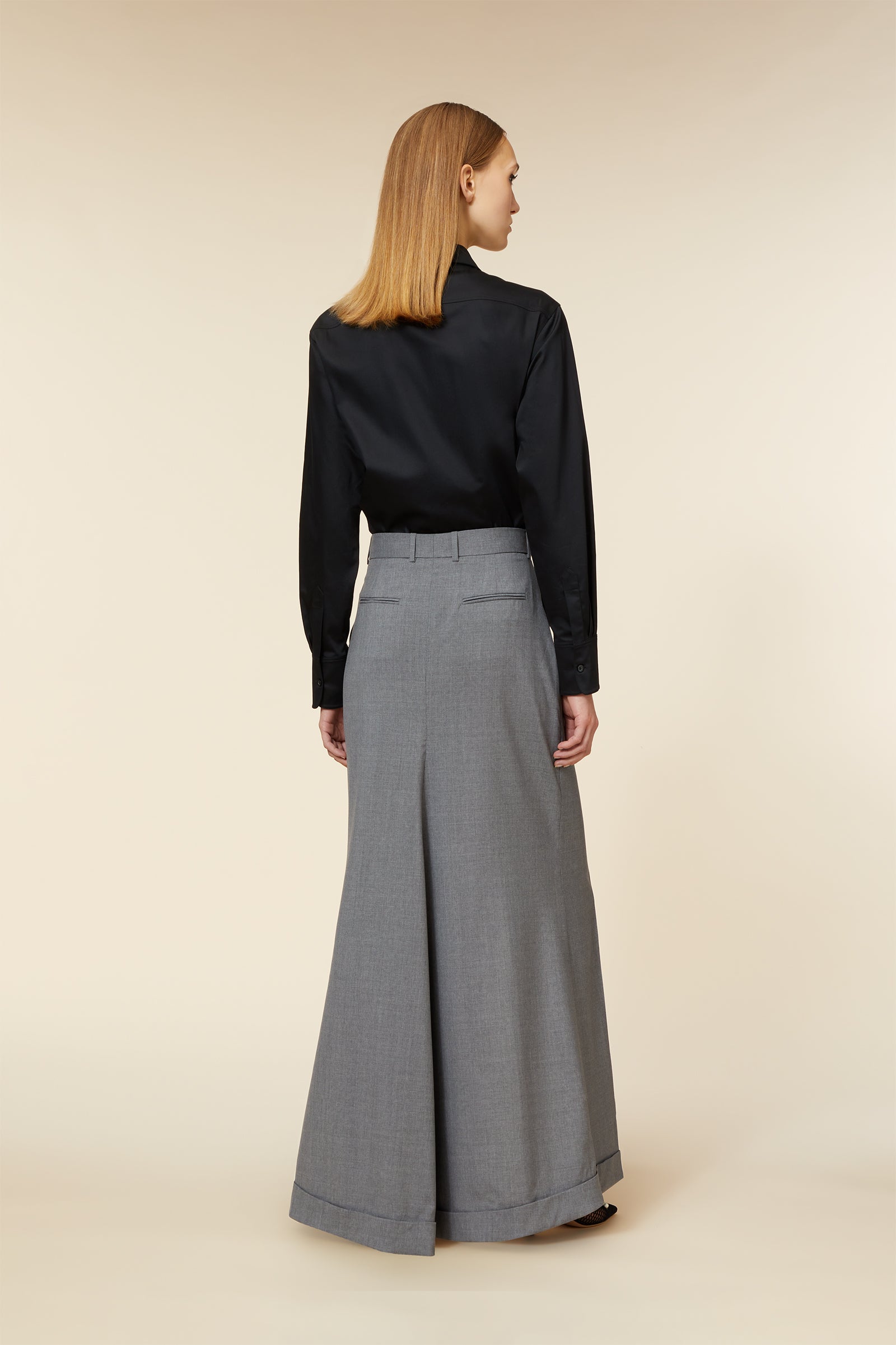 Elegant black long-sleeve blouse paired with high-waisted wide-leg gray trousers, showcasing a sophisticated office look.