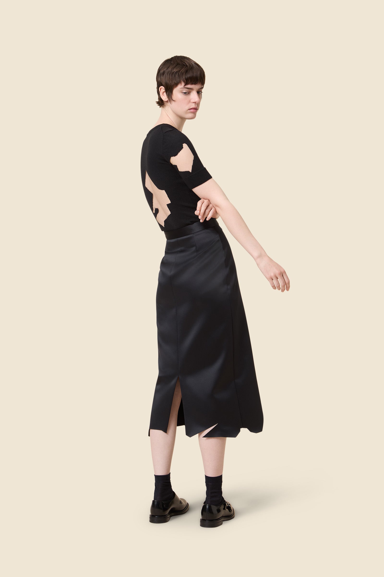 Minimalist black skirt and knit top with abstract nude patterns, featuring a sleek slit design, perfect for sophisticated styling.
