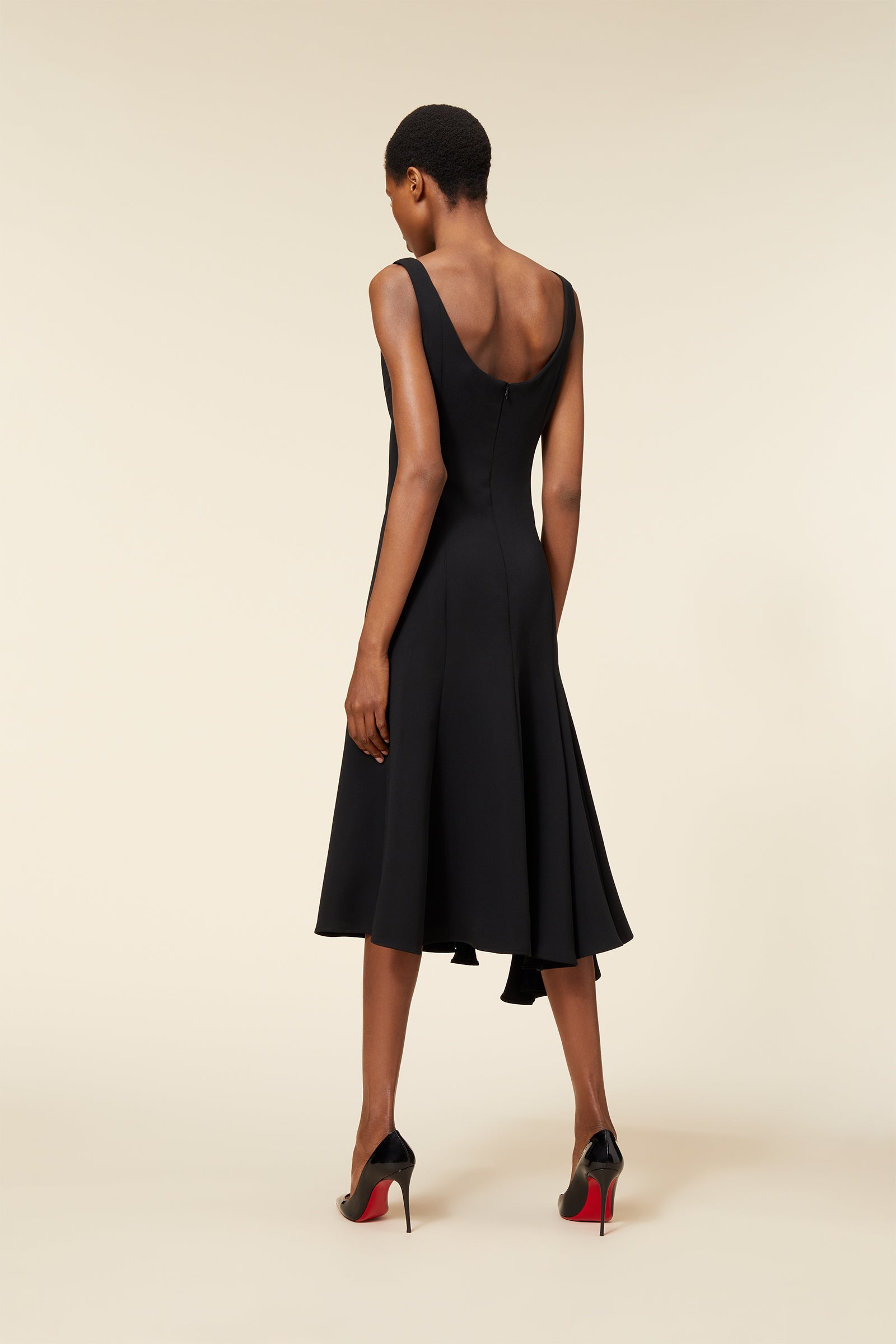 Elegant black dress with a flared midi skirt and sleeveless design, paired with sleek black stiletto heels.