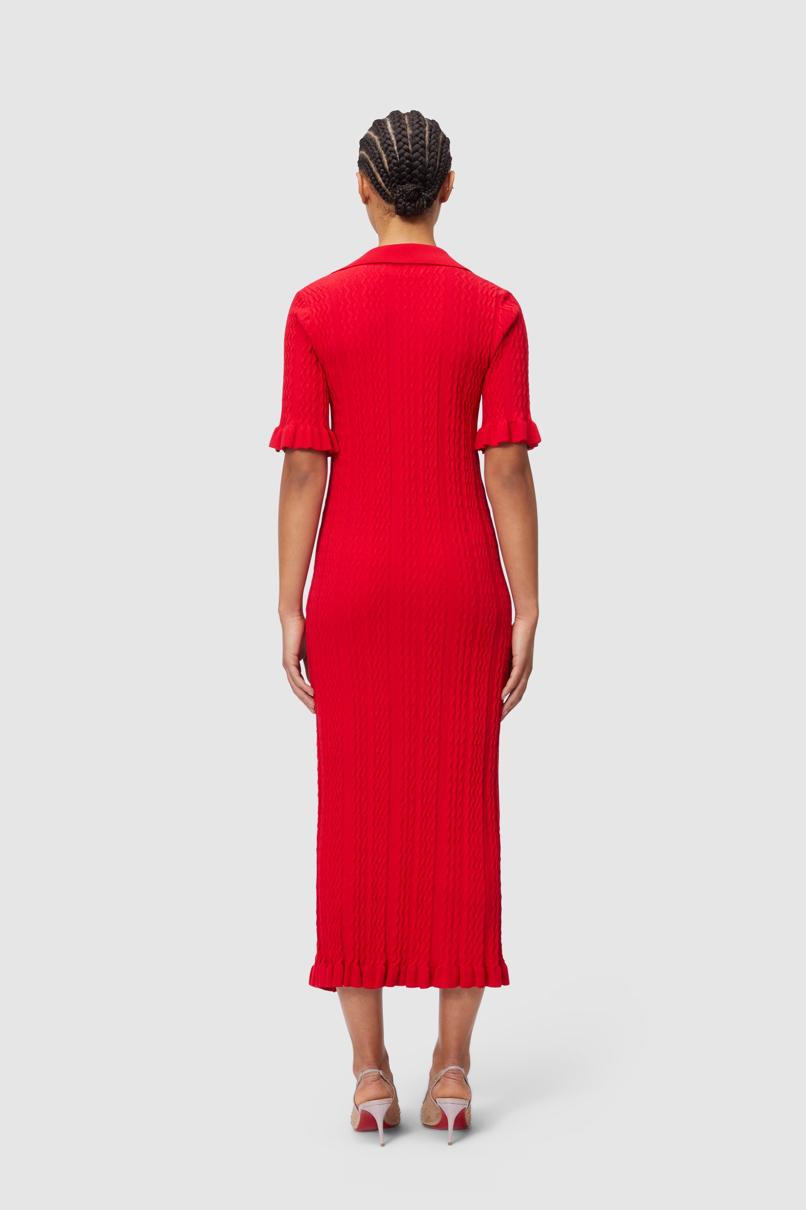 Red textured knit midi dress with short sleeves and ruffle details at cuffs and hem, showcasing a fitted silhouette.