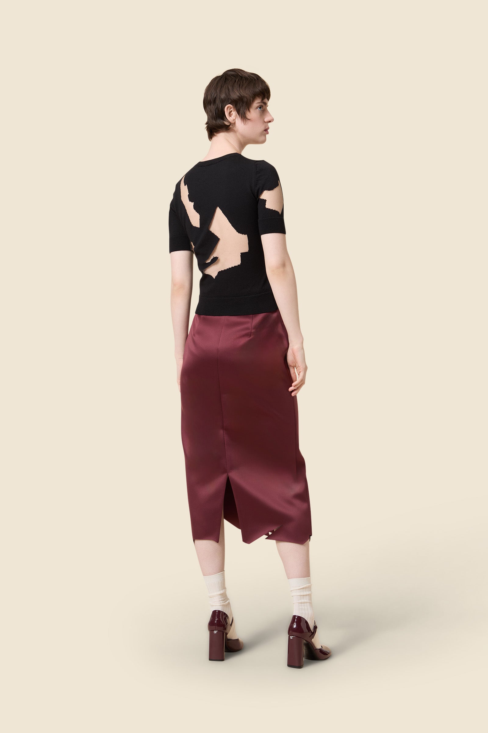 Sleek black satin dress featuring a bold geometric neckline and a fitted waist, highlighting a sophisticated style.