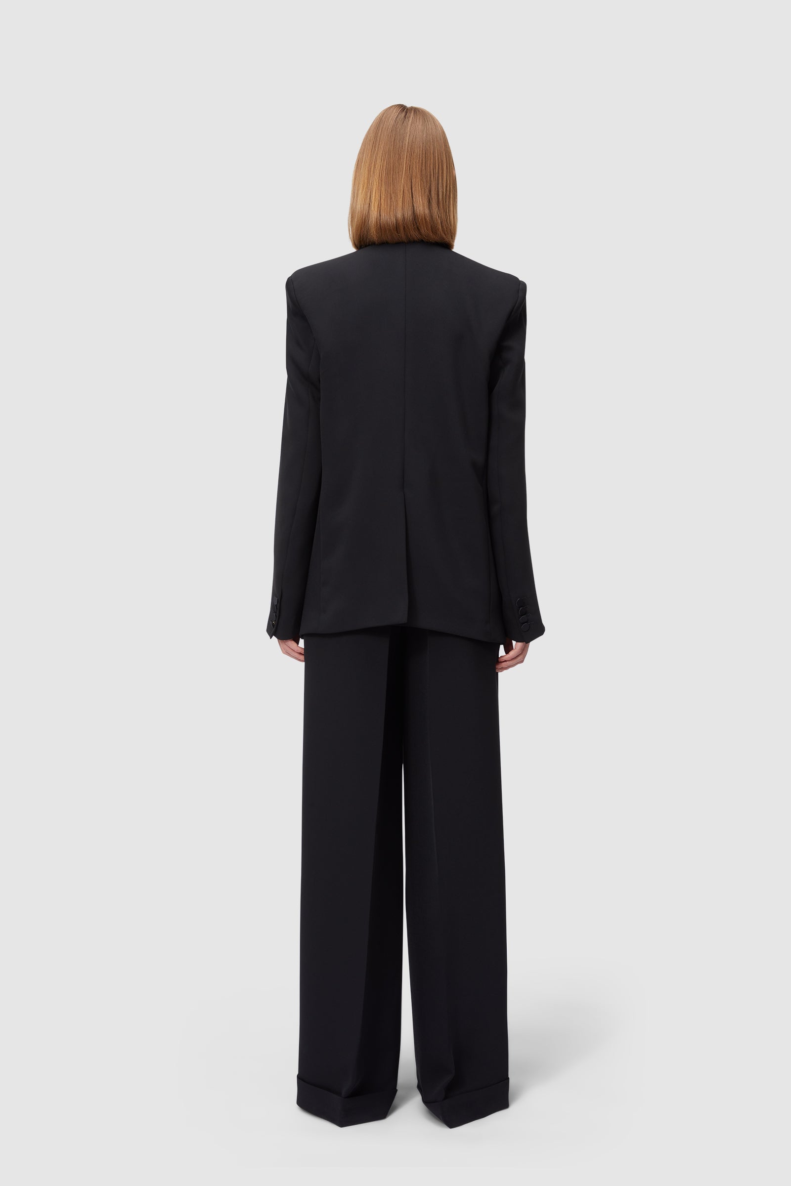 Formal black suit with tailored wide-leg trousers and structured blazer, showcasing a minimalist back view design.