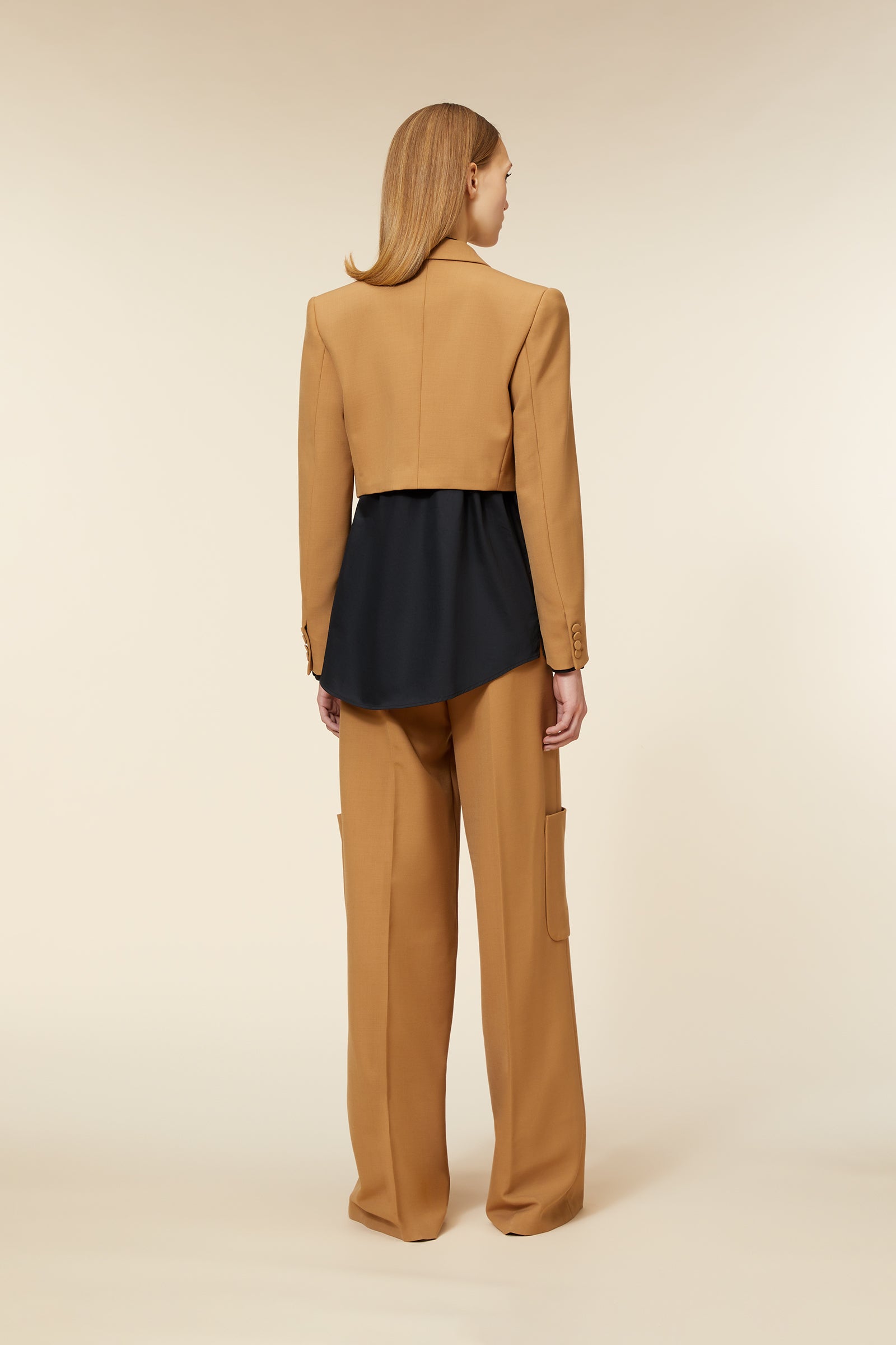 Camel cropped blazer paired with wide-leg trousers, showcasing button details and modern tailoring, over a black shirt.