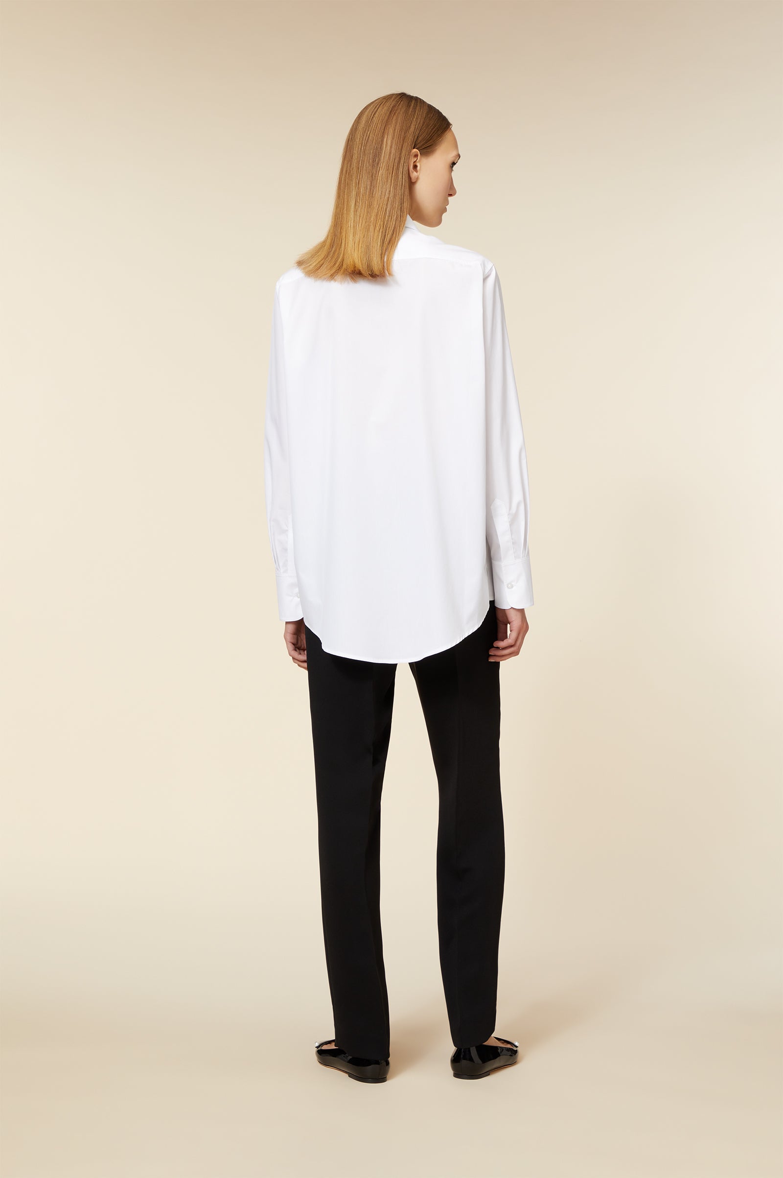 Crisp white cotton shirt with tailored fit, featuring button cuffs, paired with sleek black trousers in a minimalist style.