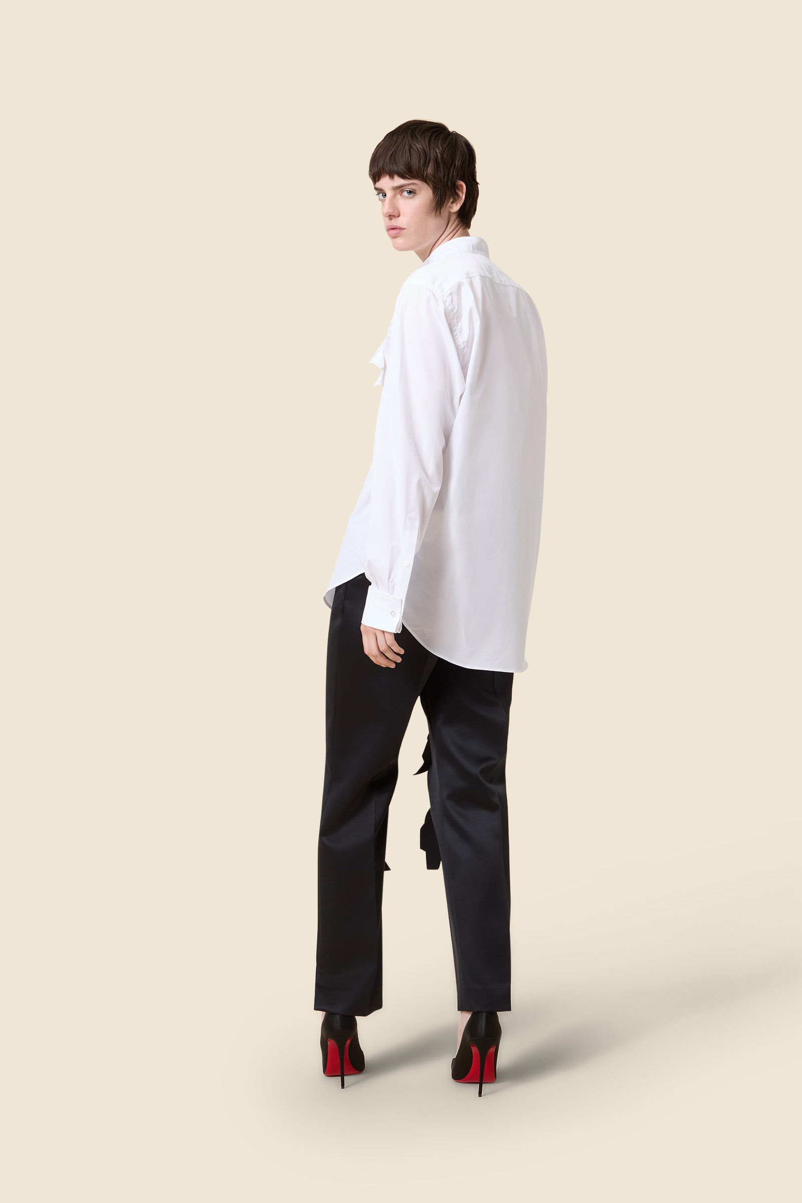Chic tailored black tuxedo jacket paired with a crisp white shirt, featuring uniquely styled cut-out black trousers.