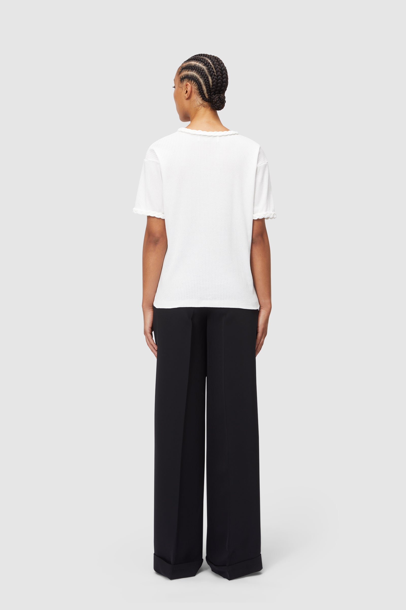 Black tailored wide-leg trousers paired with a textured white short-sleeve top featuring subtle ruffle detailing.