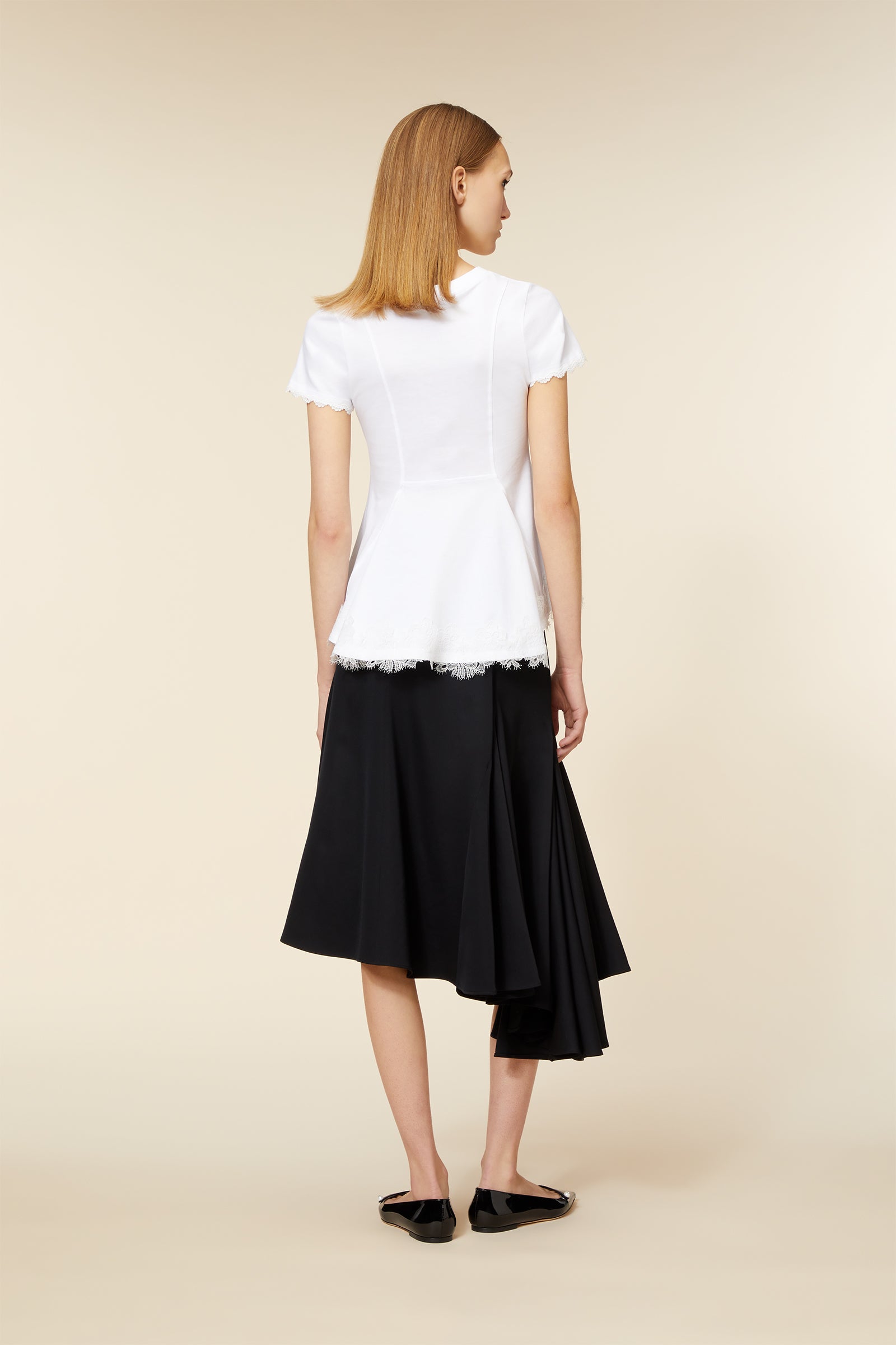 Sleek white peplum top with short sleeves paired with an asymmetrical flowing black skirt and black ballet flats.