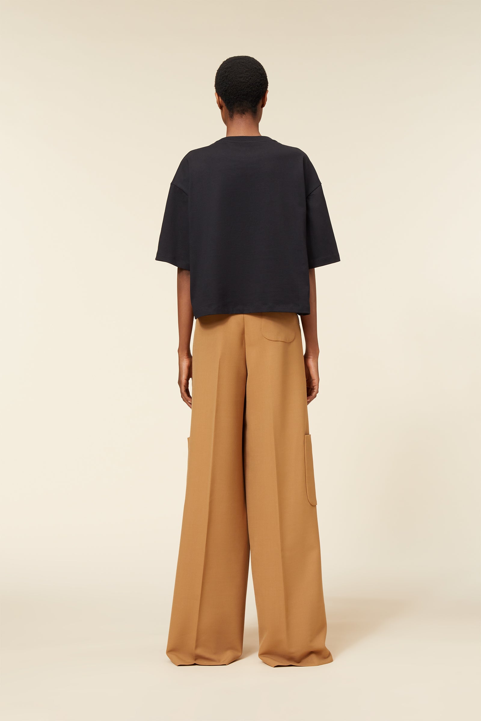 Black oversized T-shirt paired with wide-leg tan trousers, featuring utility pocket details for a chic, relaxed look.