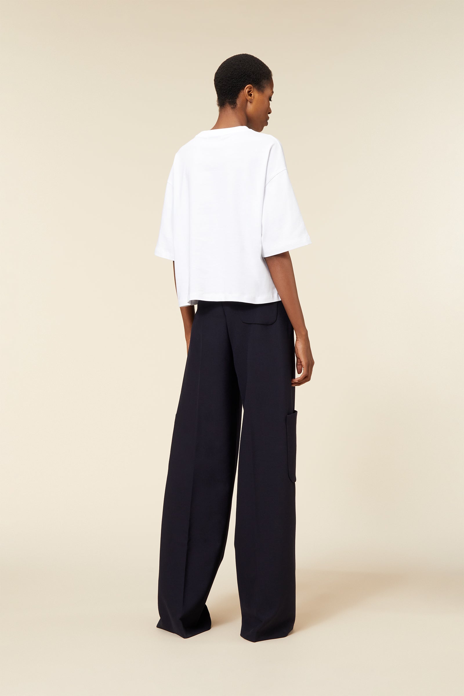 Loose-fit white cotton T-shirt paired with wide-legged black wool pants featuring oversized pocket detailing.