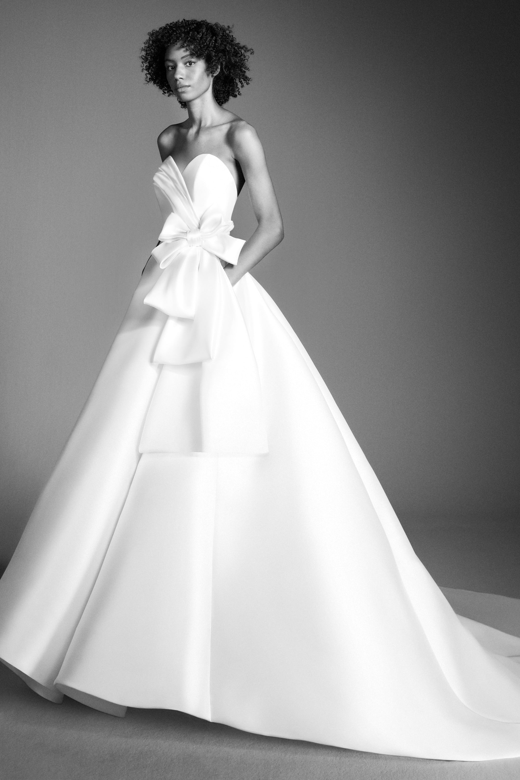 Crafted out of mikado, this gown features an intricately draped sweetheart bodice that leads way to a royal ribbon bow