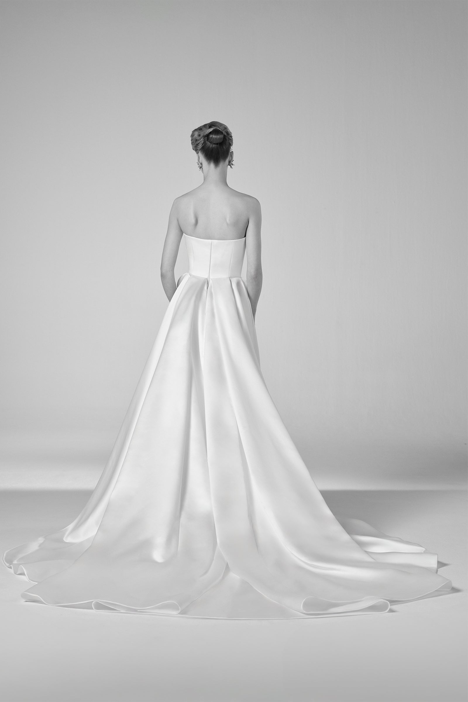 This elegant gown showcases a sleek bonded satin column skirt beneath a gracefully draped layer, knotted at the waist for a refined touch, from the Viktor&Rolf Mariage collection.