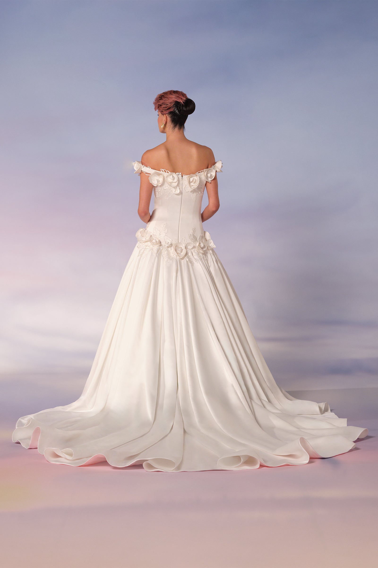 This breathtaking bonded satin gown is embellished with delicately handcrafted lace pansies, featuring intricate cut-out details and sculpted blossoms with shimmering embroidered petals and foliage, adorning the off-shoulder neckline and dropped waist, from the Viktor&Rolf Mariage collection.