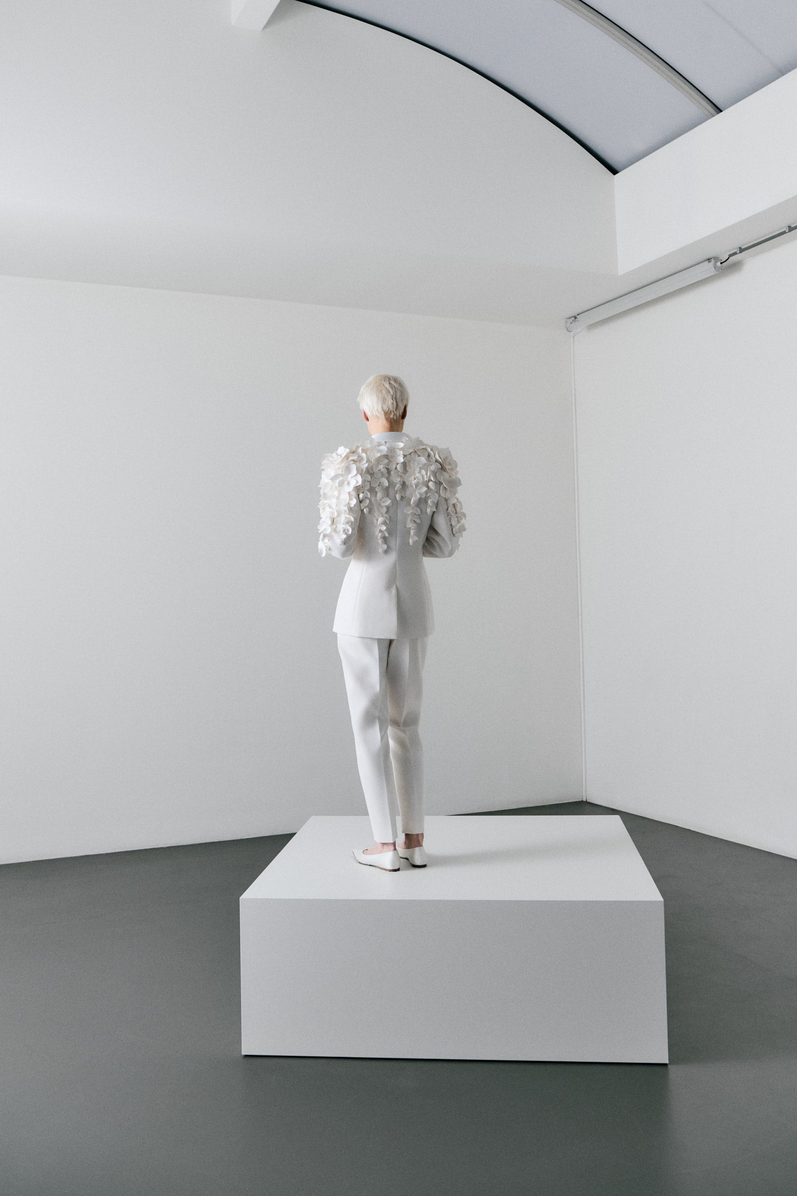 White floral embroidered suit on a model against a plain background