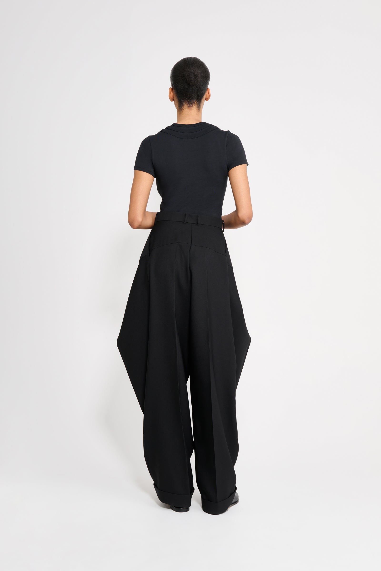 Model wearing a black tshirt with black pants on a white background.