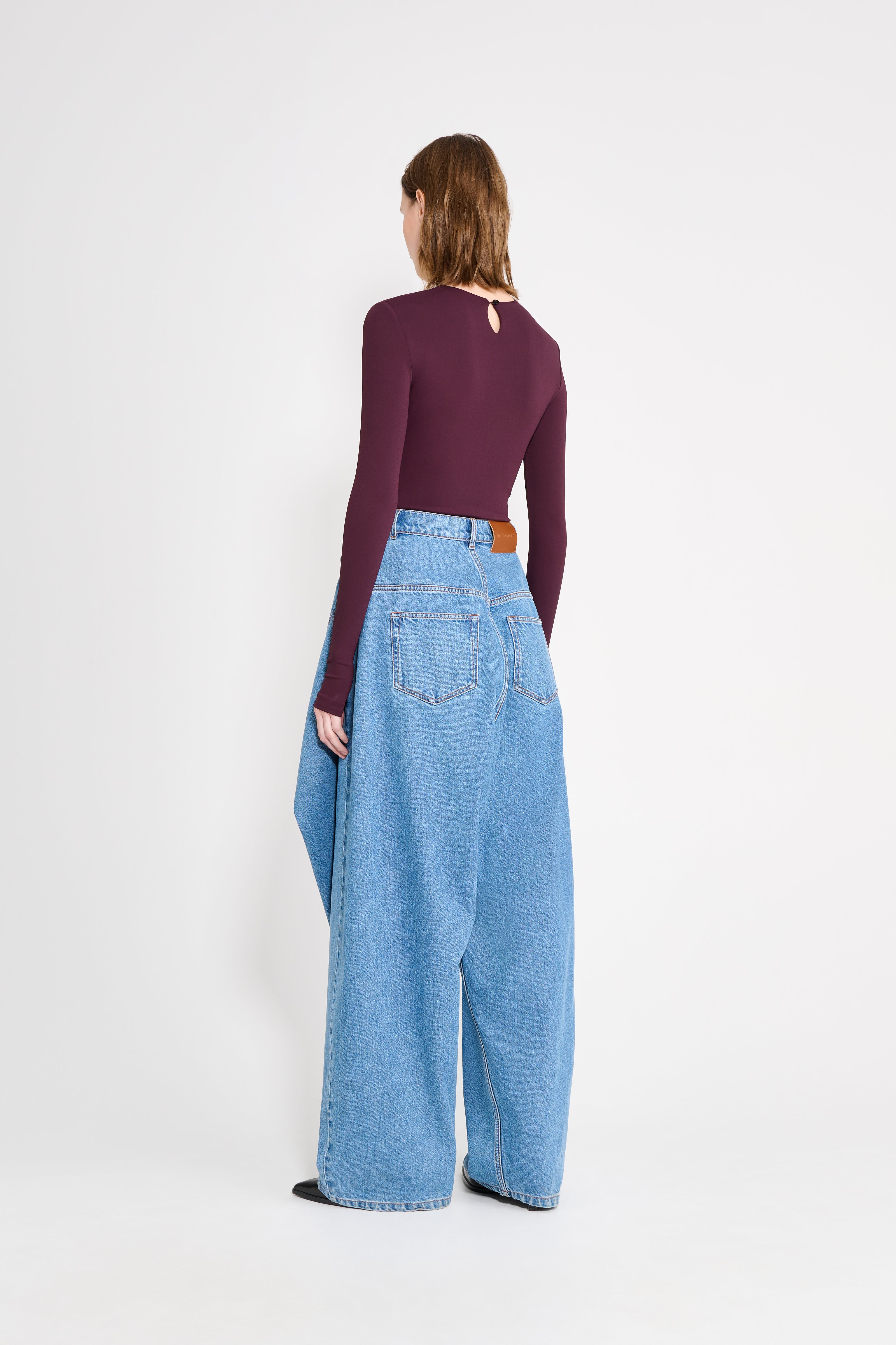 Person wearing a purple top and light blue jeans on a white background