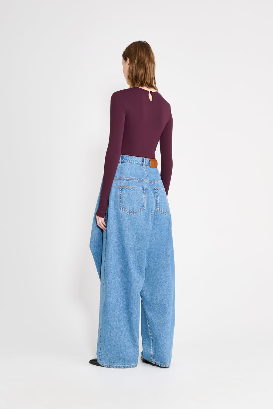 Person wearing a purple top and light blue jeans on a white background