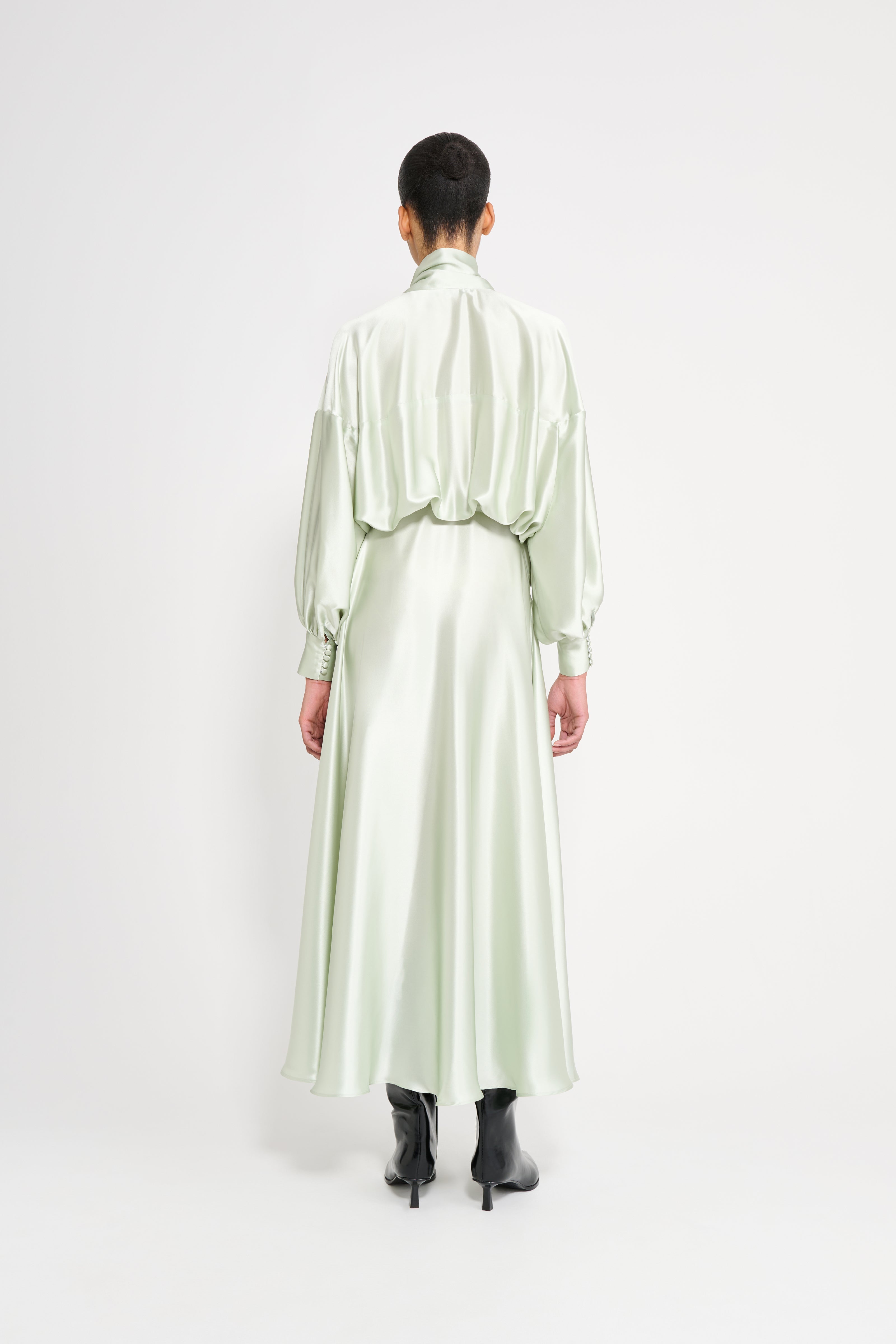 Person wearing a light green satin dress on a white background
