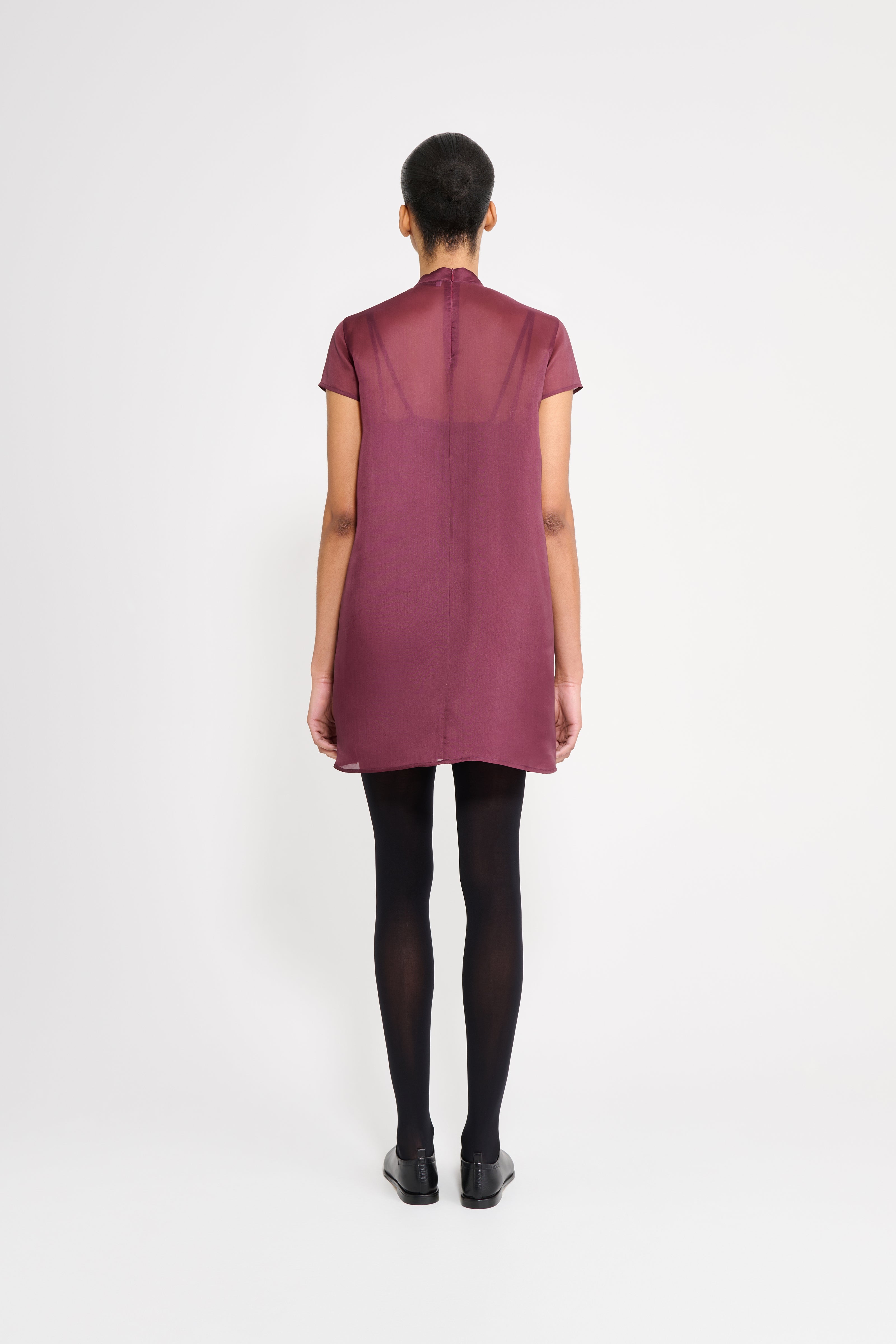 Person wearing a maroon dress on a white background