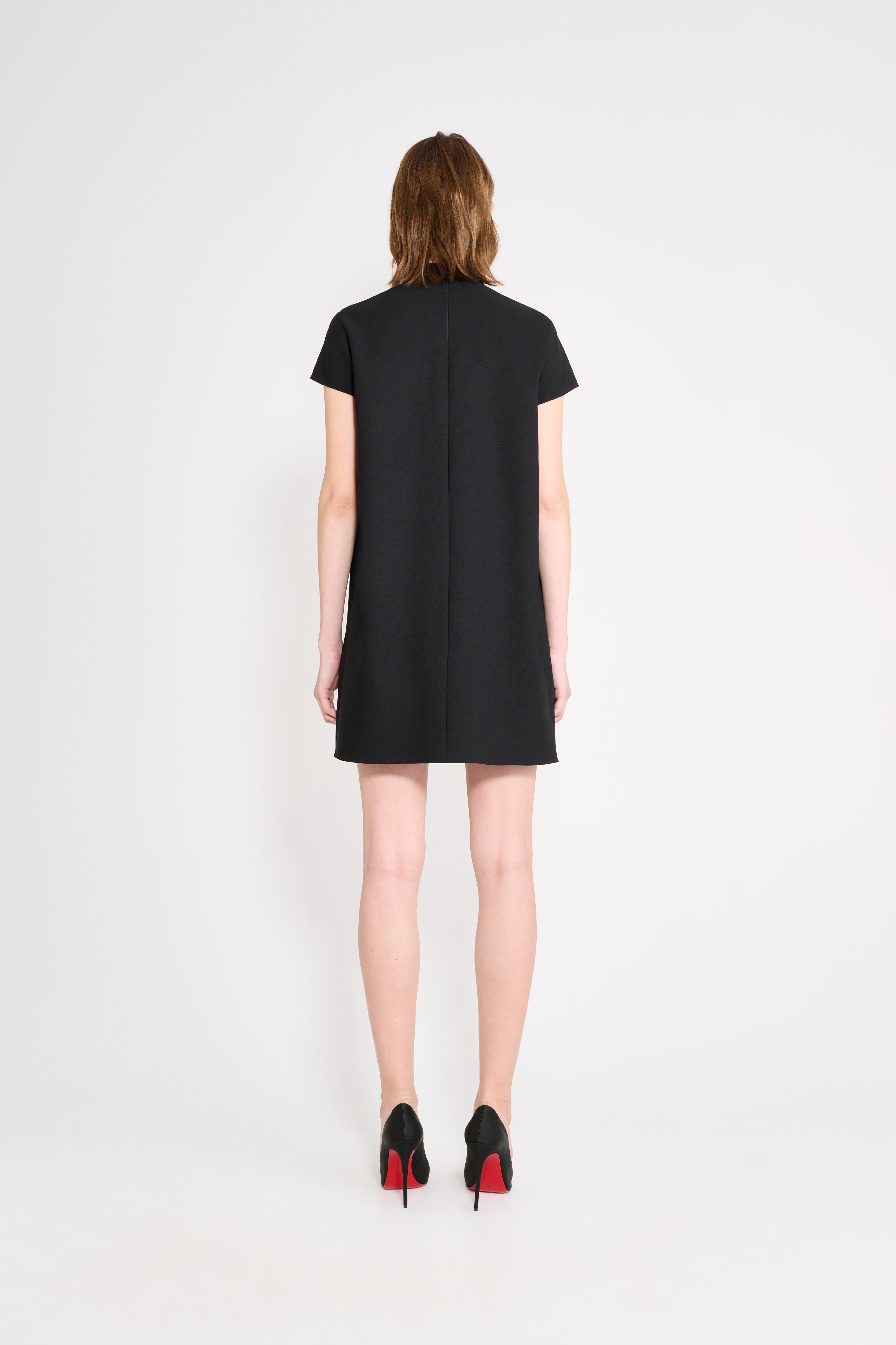 Model wearing a black dress shown from the back.